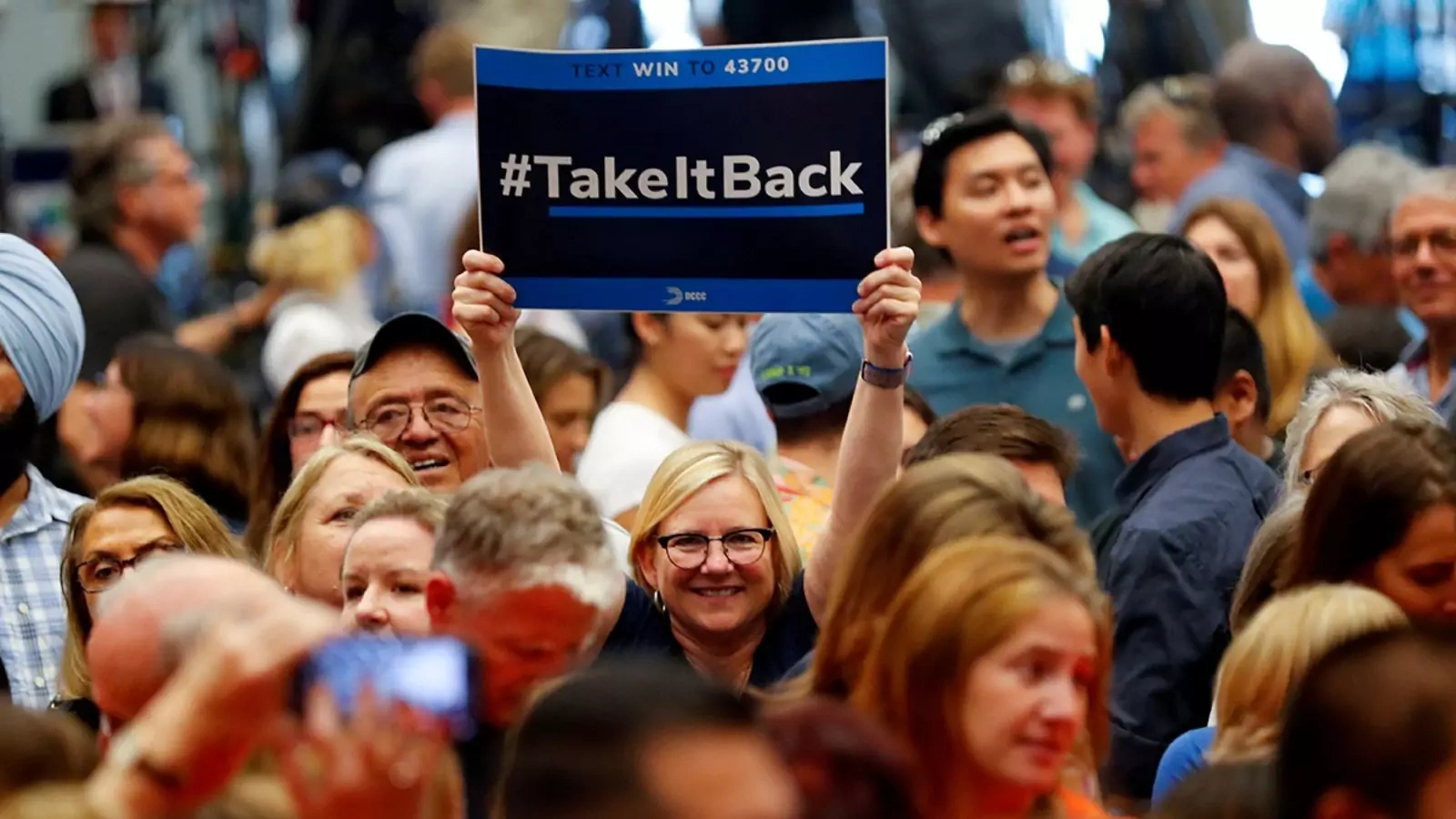  A woman holds up a "Take It Back" sign at a political rally with former President Barack Obama in Anaheim, California.