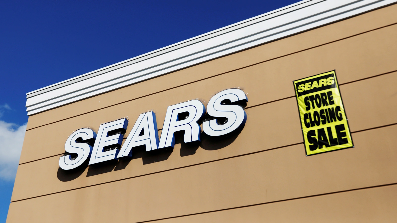 A store closing sale sign is posted next to a Sears logo in New Hyde Park, New York.