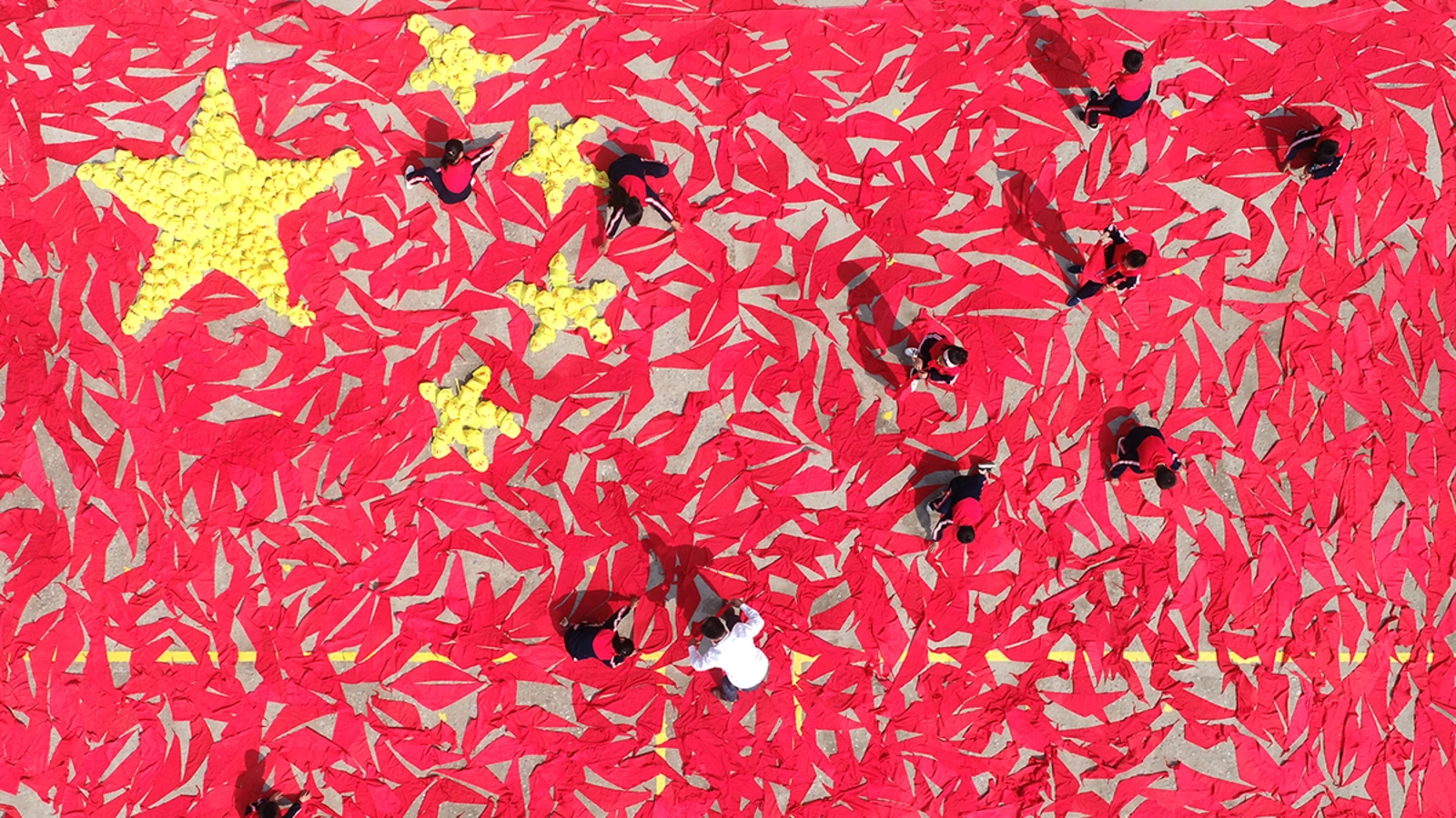 Students use red scarves and yellow hats to make the pattern of the Chinese national flag at a primary school in Linyi, Shandong Province. 