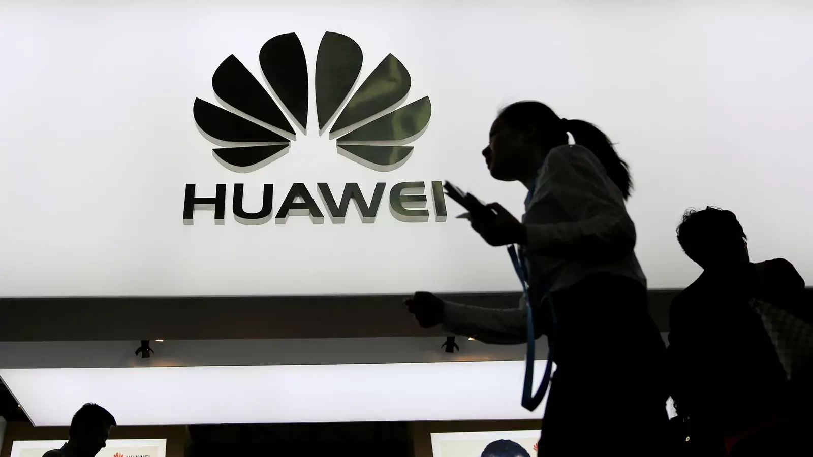People walk past a sign board of Huawei at CES (Consumer Electronics Show) Asia 2016 in Shanghai, China.