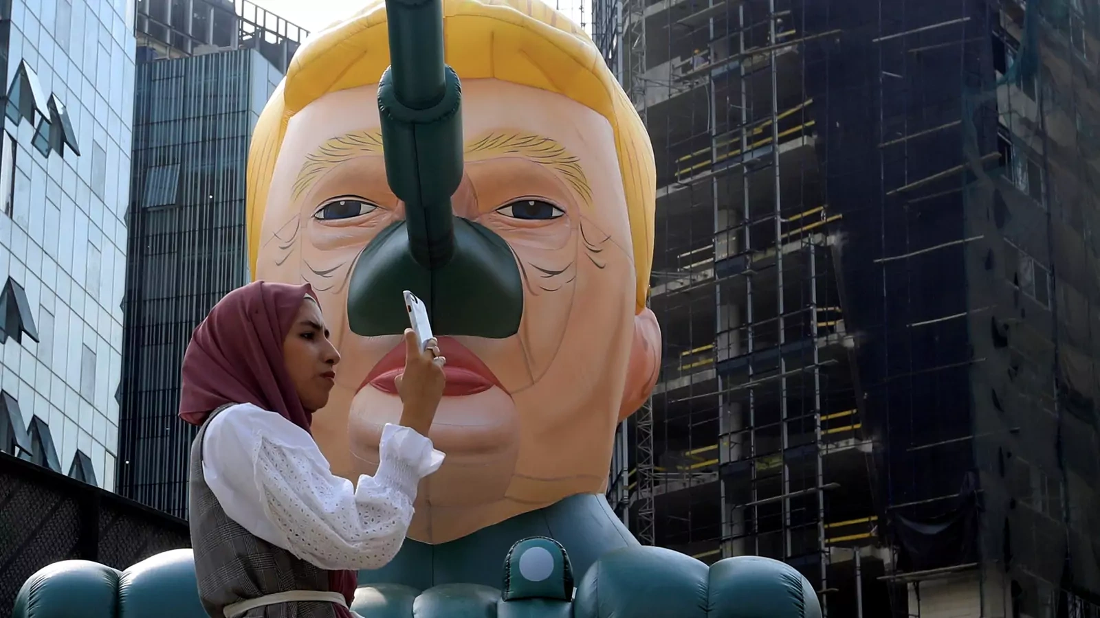 A woman stands next to an inflatable tank with U.S. President Donald Trump outside an art exhibition 'MonuMental' by the pseudonymous artist, Saint Hoax in downtown Beirut, Lebanon October 12, 2018