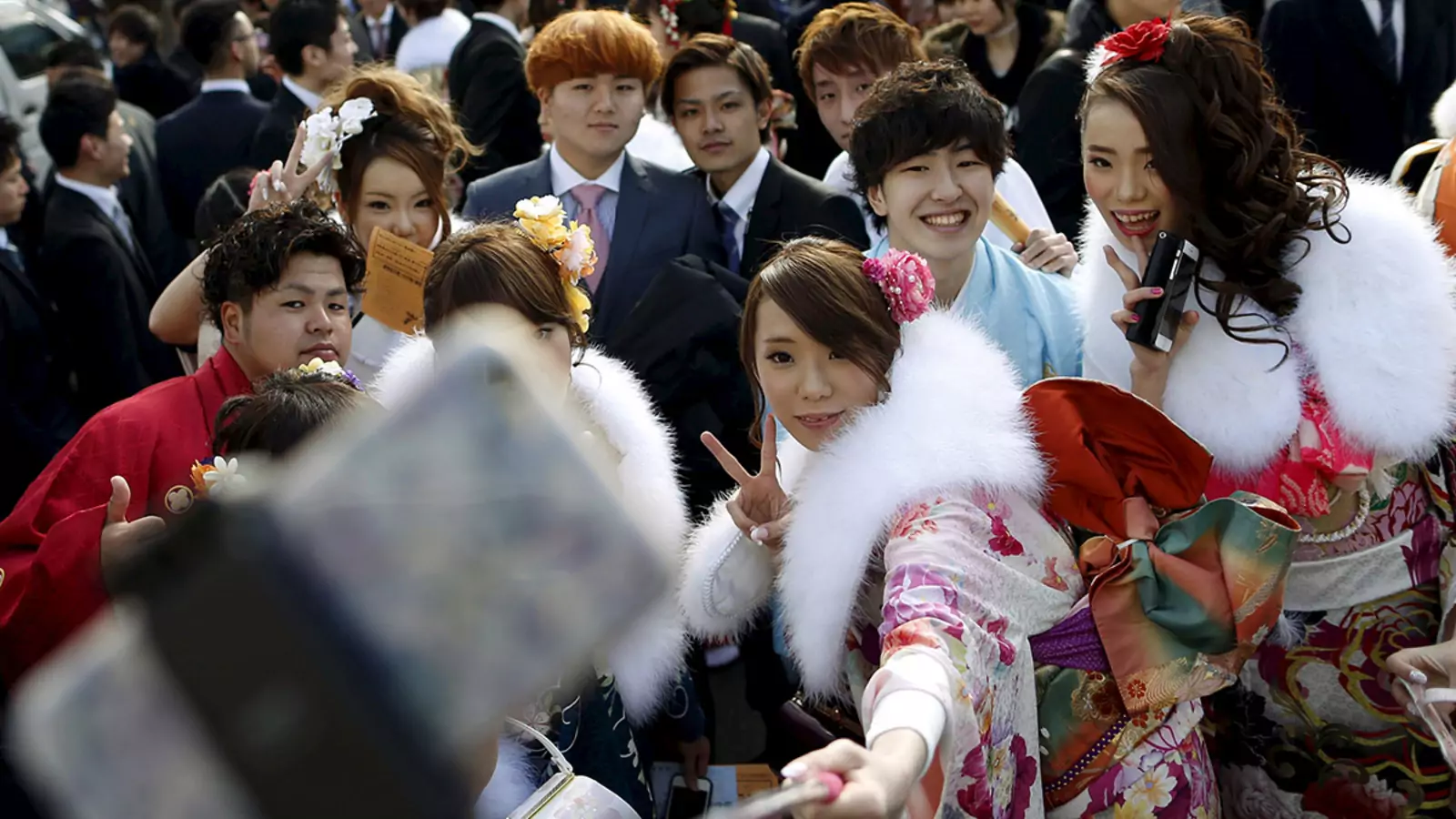 Young people pose for selfies in a park in Tokyo.