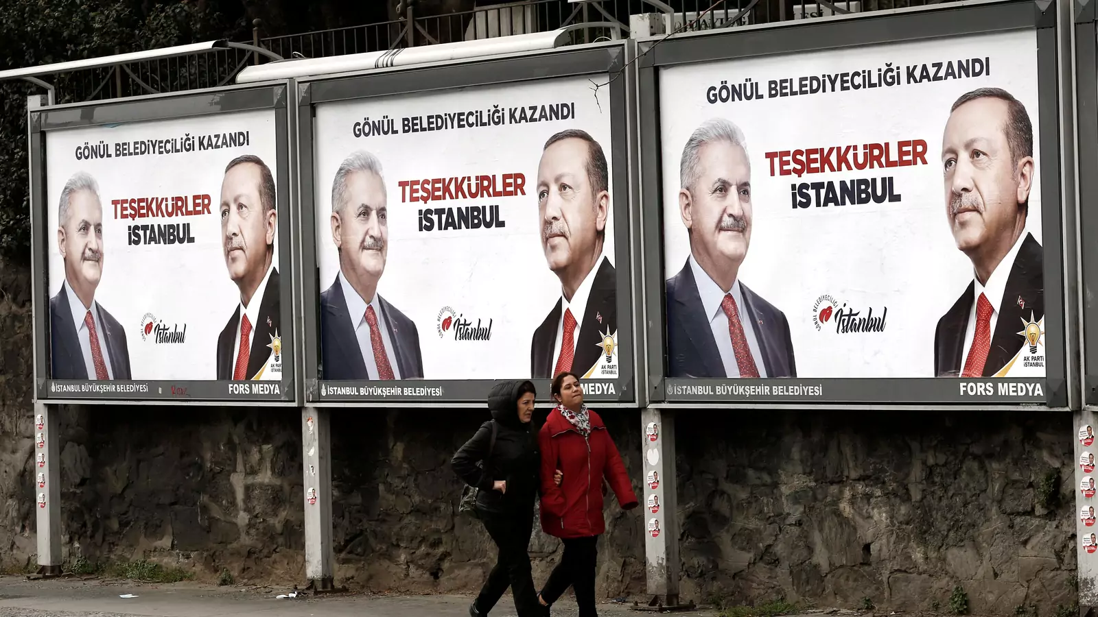 People walk past by AK Party billboards with pictures of Turkish President Tayyip Erdogan and mayoral candidate Binali Yildirim in Istanbul, Turkey, April 1, 2019.