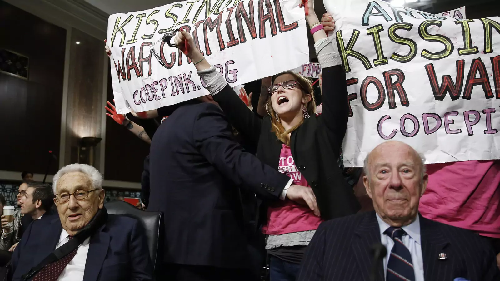 Code Pink demonstrators surround former United States Secretaries of State Henry Kissinger (L) and George Shultz (R) before the beginning of the Senate Armed Services Committee on global challenges and U.S. national security strategy on Capitol Hill