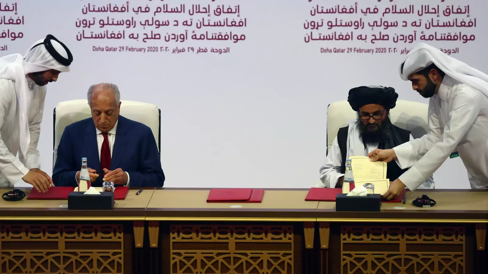 Mullah Abdul Ghani Baradar, the leader of the Taliban delegation, signs an agreement with Zalmay Khalilzad, U.S. envoy for peace in Afghanistan, at a signing agreement ceremony between members of Afghanistan's Taliban and the U.S. in Doha, Qatar. 