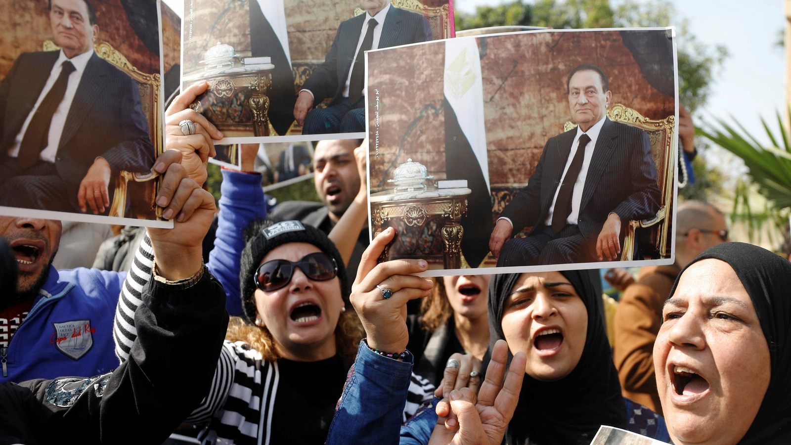 Supporters of former Egyptian President Hosni Mubarak hold his photos near the main gate of a cemetery during his burial ceremony, east of Cairo, Egypt February 26, 2020.