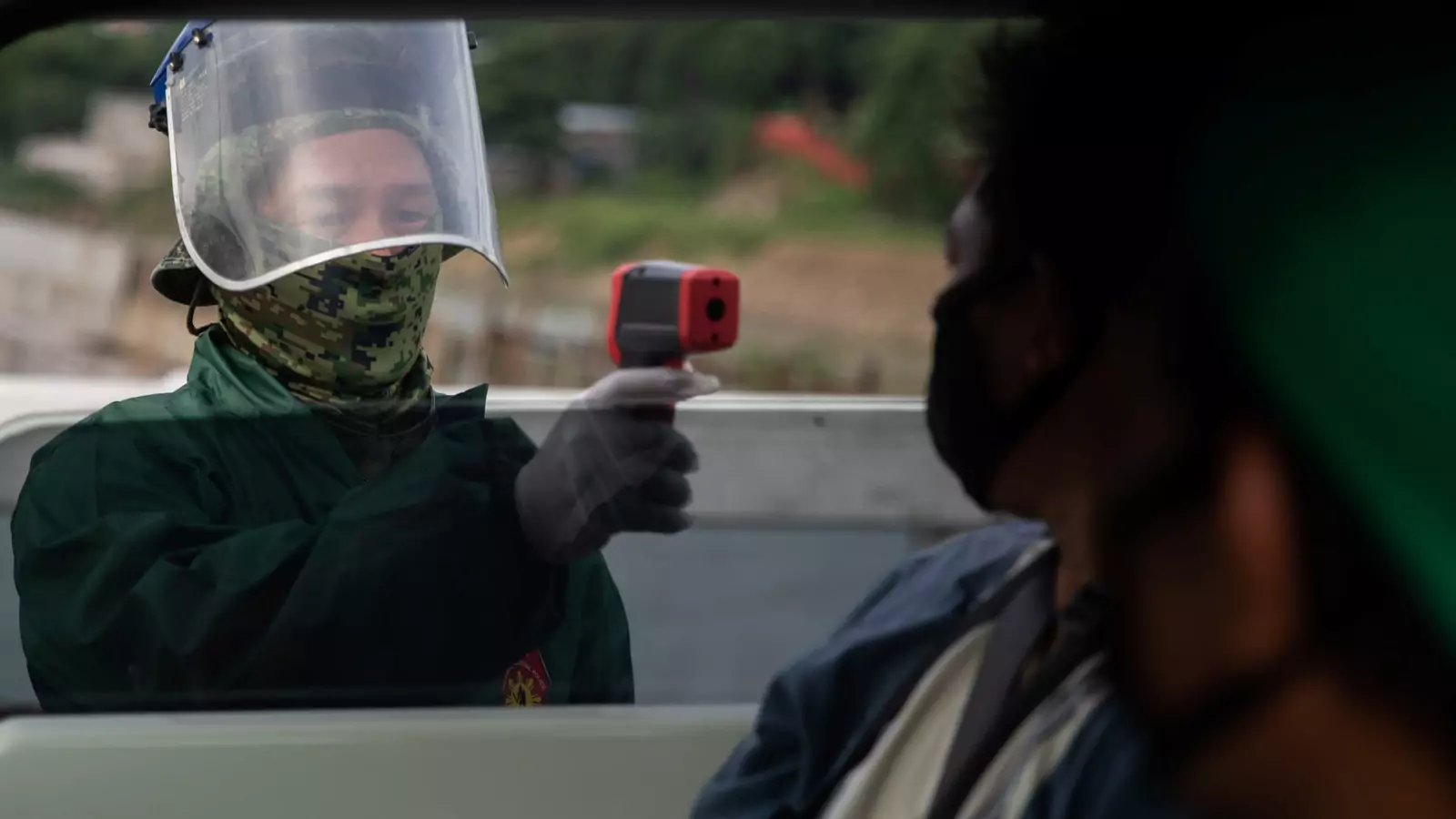 A police officer checks a passenger's body temperature at a quarantine checkpoint amid the reimposed strict lockdown to curb COVID-19 infections, in Quezon City, Metro Manila, Philippines, on August 5, 2020.