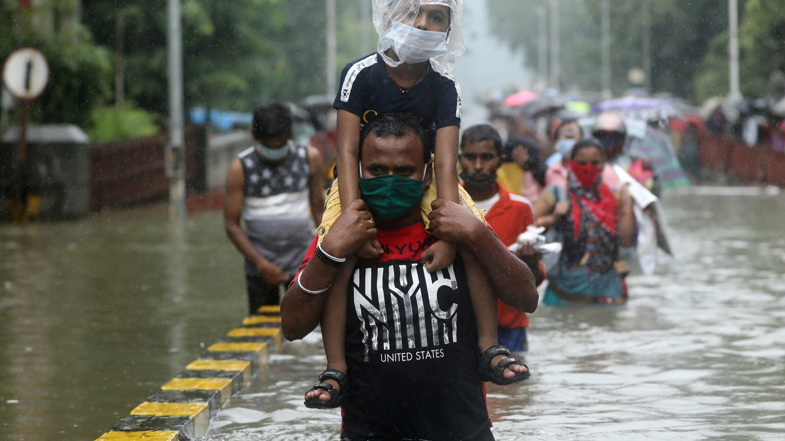 A man carries a child through a waterlogged road after heavy rainfall in Mumbai, India on September 23, 2020.