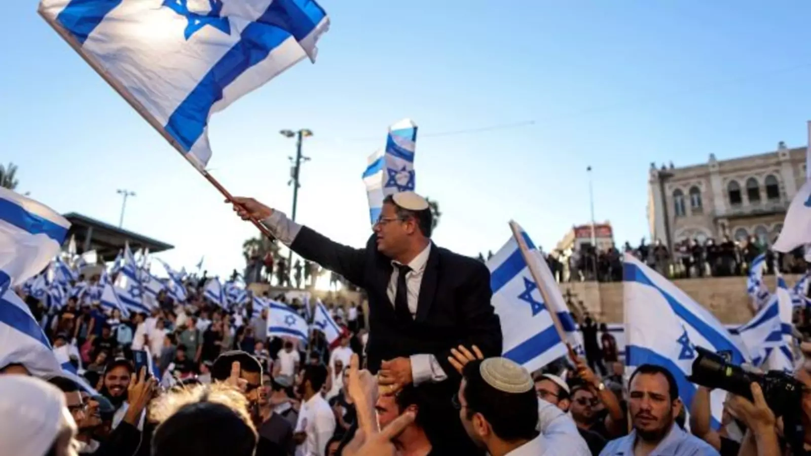 Israeli lawmaker Itamar Ben Gvir carries an Israeli flag as he dances together with others by Damascus gate just outside Jerusalem's Old City June 15, 2021.