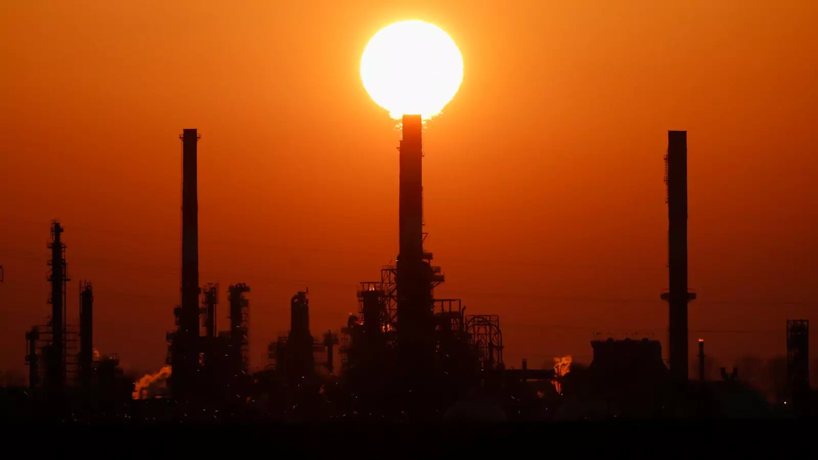 The sun sets behind the chimneys of the Total Grandpuits oil refinery, southeast of Paris, France, March 1, 2021.