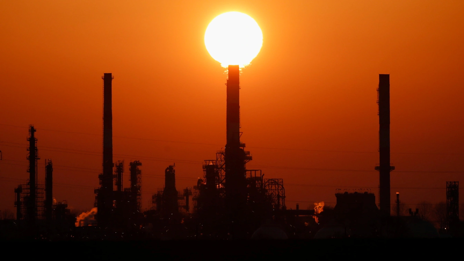 The sun sets behind the chimneys of the Total Grandpuits oil refinery, southeast of Paris, France, March 1, 2021.