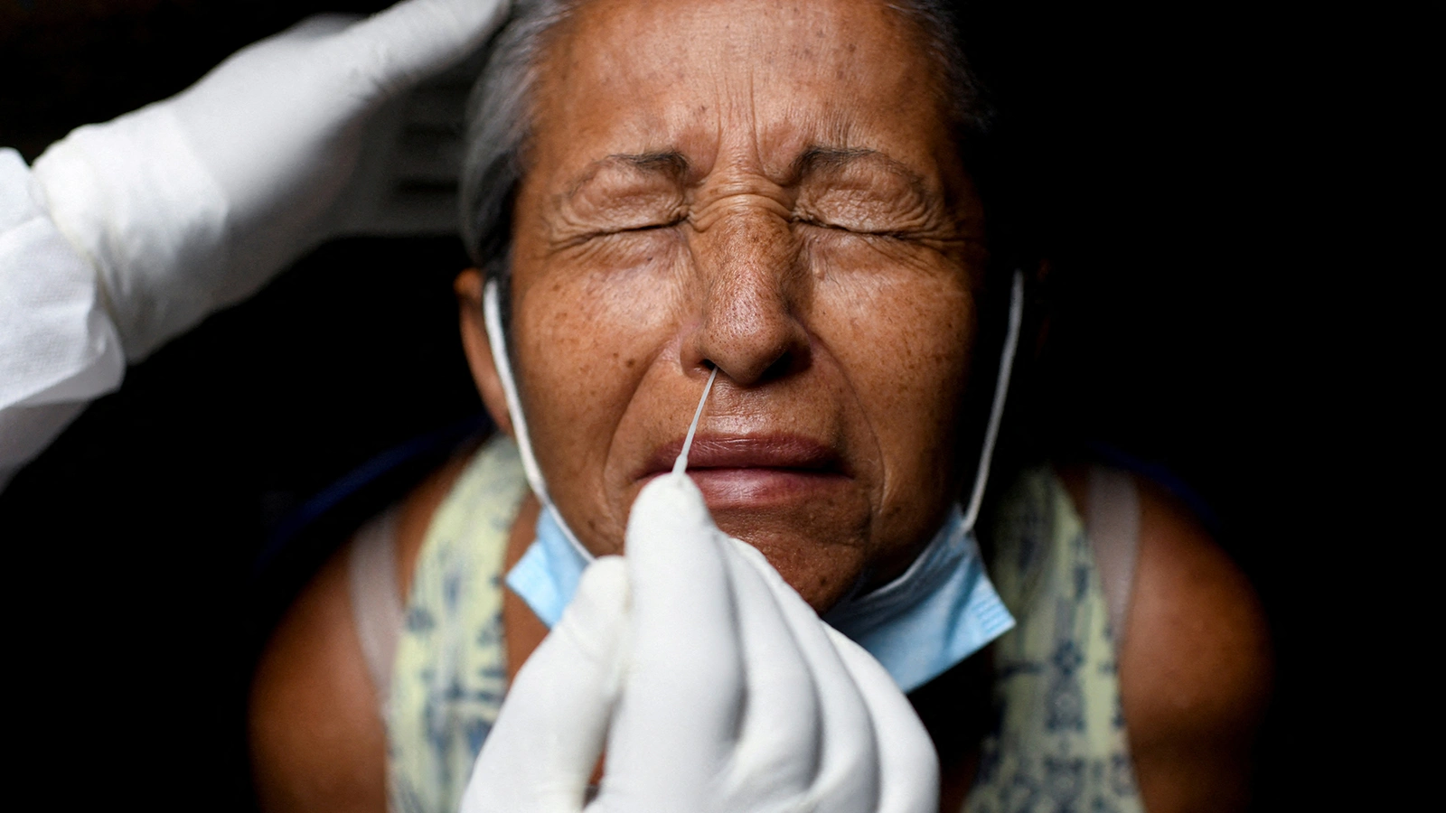 A health-care worker in Rio de Janeiro takes a swab sample to test a person for COVID-19.