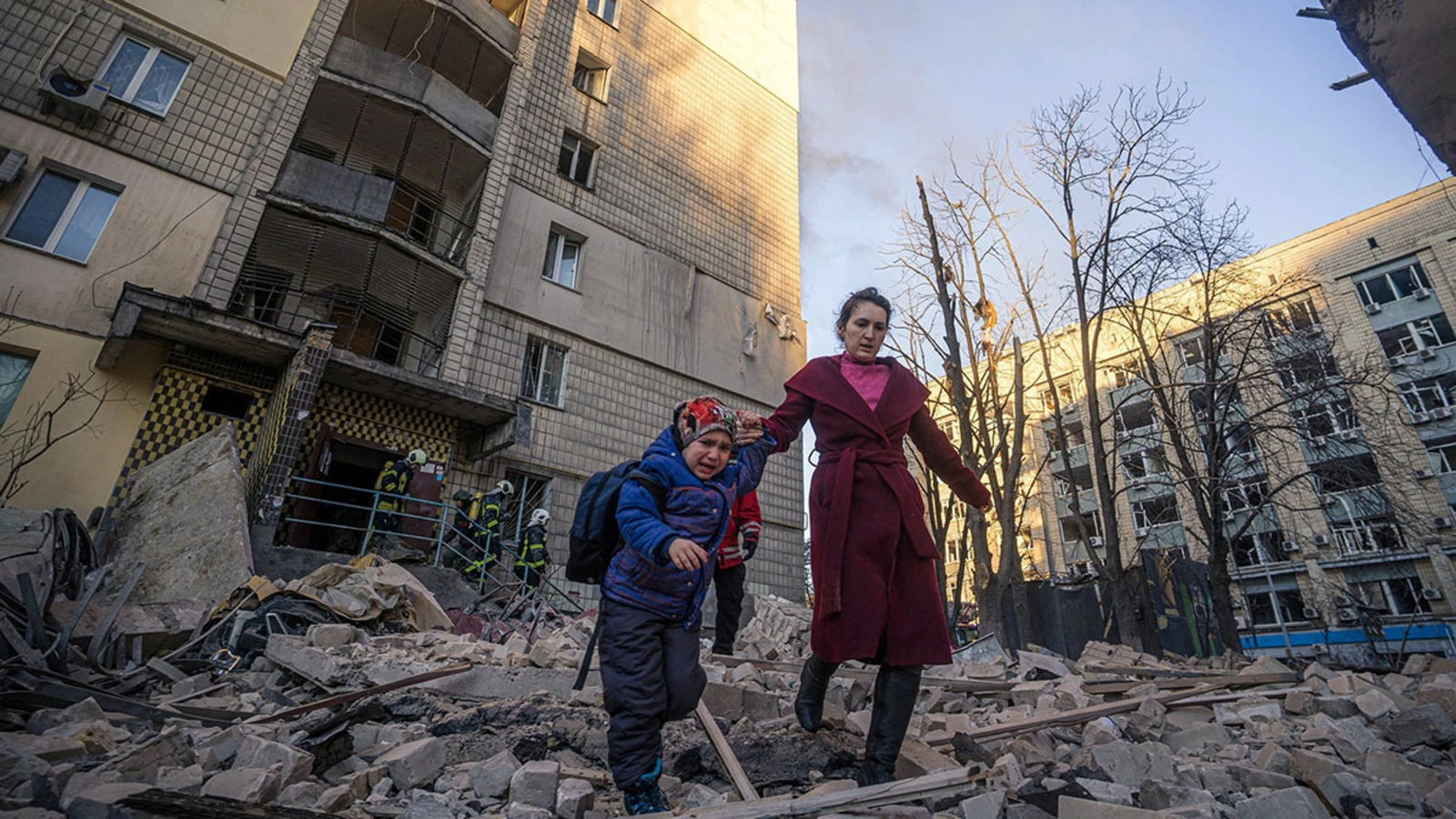 A woman with a child evacuates from a residential building damaged by shelling by Russian forces in Kyiv, Ukraine, in March 2022.