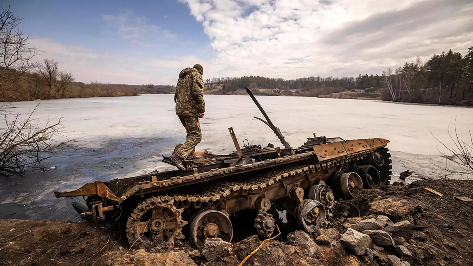 A Ukrainian serviceman stands near a destroyed Russian tank in the northeastern city of Trostianets, on March 29, 2022