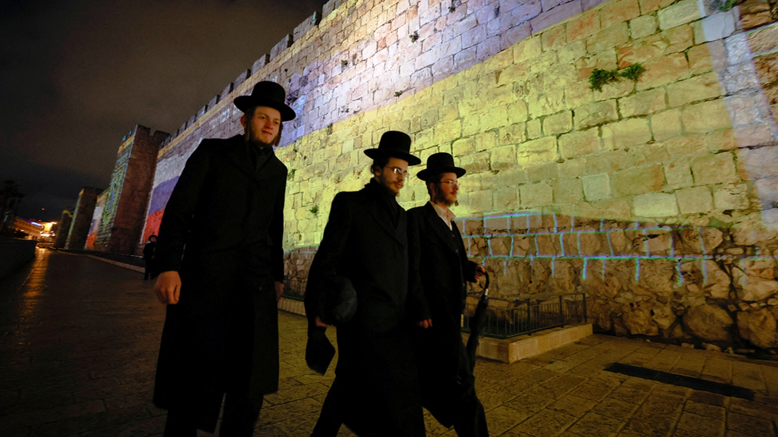 People walk past projections of the national flags of Russia and Ukraine on the walls of Jerusalem’s Old City.