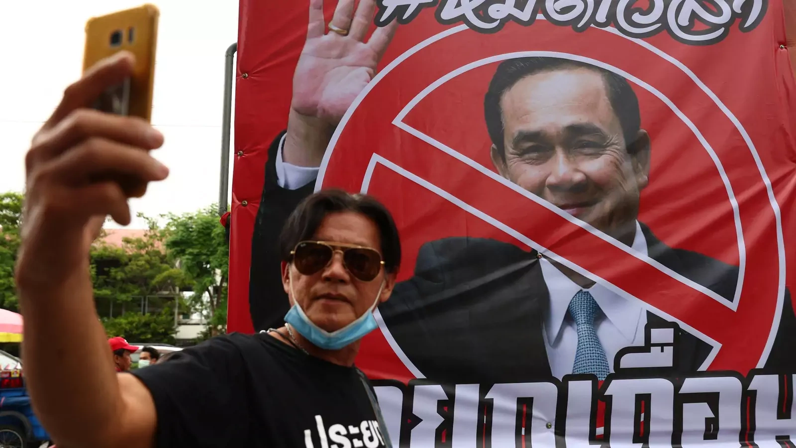 A protester takes a picture next to a picture of Thailand's Prime Minister Prayuth Chan-ocha outside the Government House, as the Constitutional Court suspended Prime Minister Prayuth Chan-ocha from official duties, in Bangkok, Thailand, August 24, 2022. 