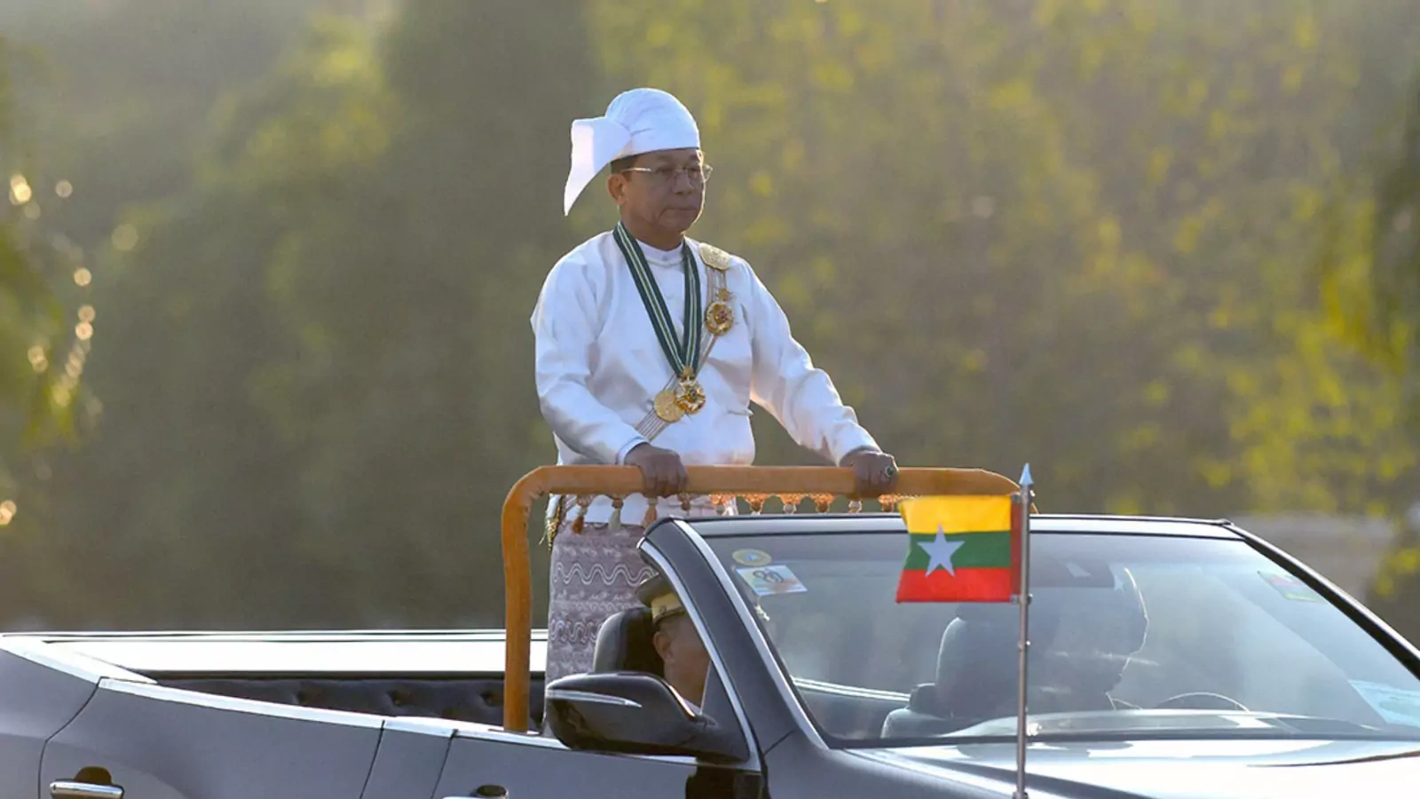 Myanmar's military chief Min Aung Hlaing stands in a car as he oversees a military display at a parade ground to mark the country's Independence Day in Naypyidaw on January 4, 2023.