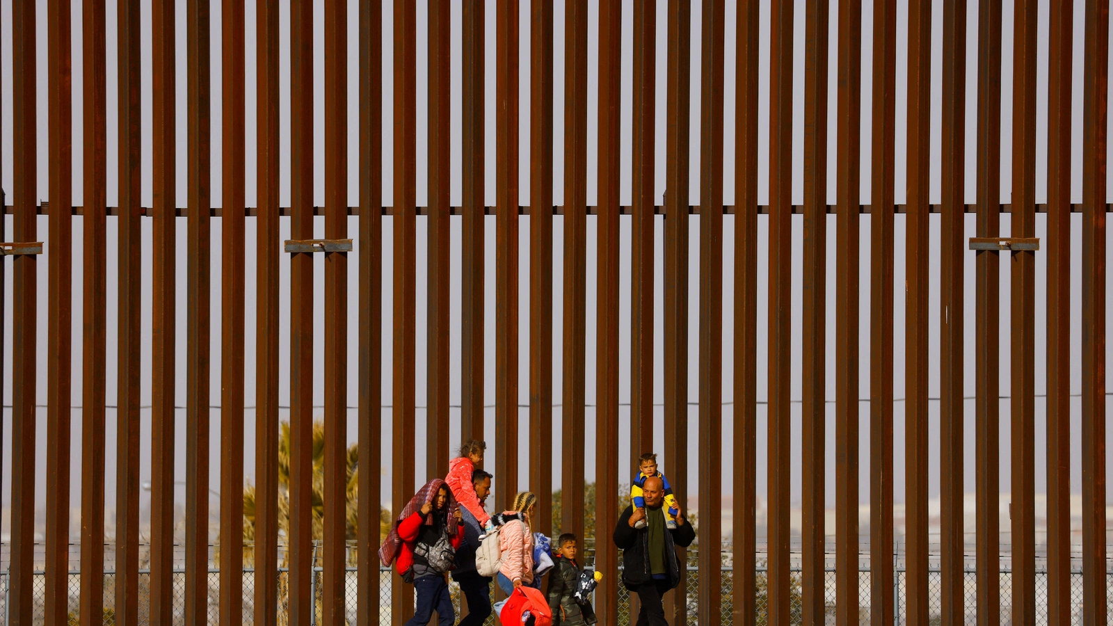 The Hernandez family, Venezuelan migrants seeking asylum in the U.S. who were not received for the appointment they got using the U.S. Customs and Border Protection (CBP) CBP One application, walk next to the border wall after crossing the Rio Bravo river