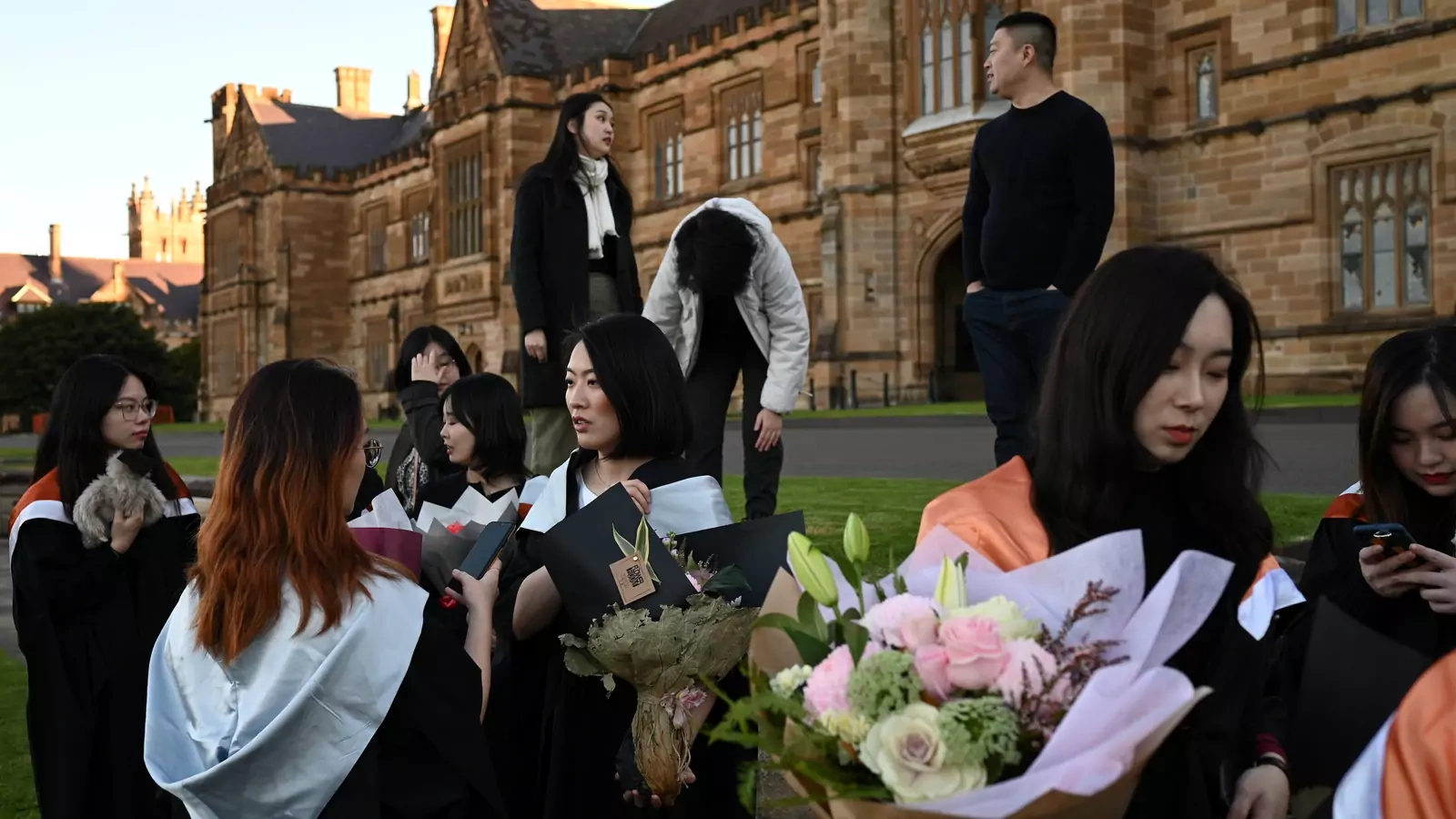 Shiyu Bao (center) and her fellow classmates, who are international students from China, get ready to take pictures in their graduation gowns around campus at the University of Sydney in Sydney, Australia, on July 4, 2020.