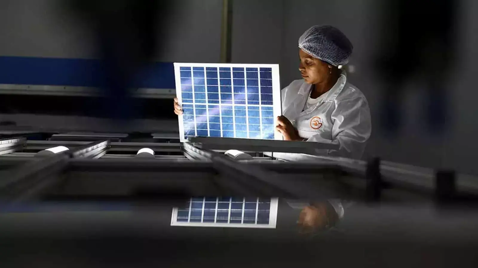 A woman looks over a solar panel at an women-run solar panel factory in Cape Town, South Africa.