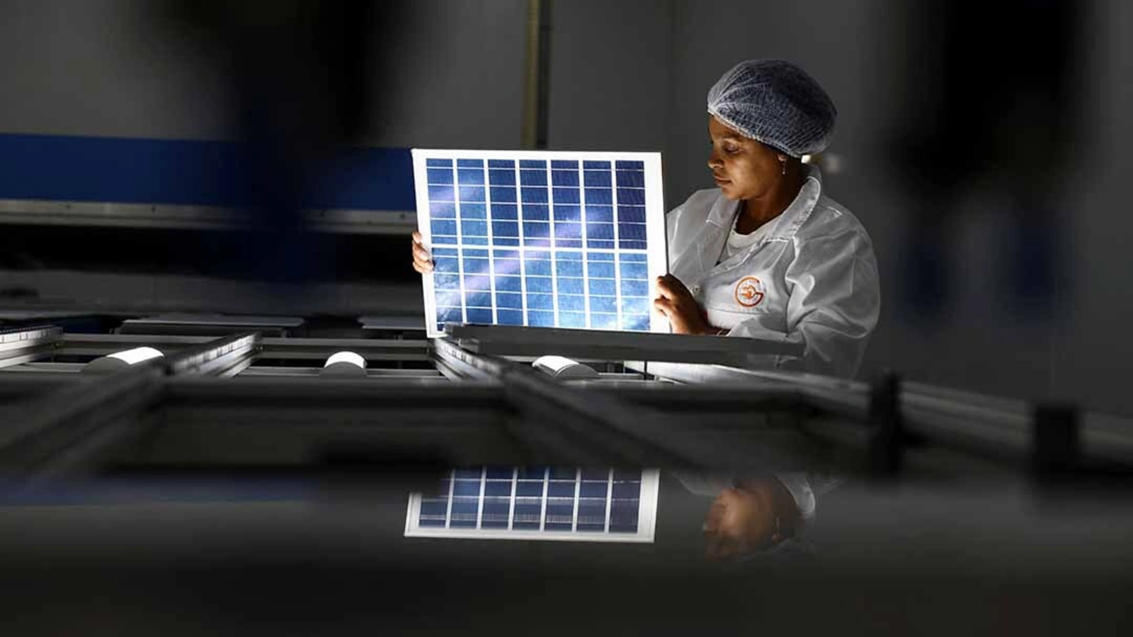 A woman looks over a solar panel at an women-run solar panel factory in Cape Town, South Africa.