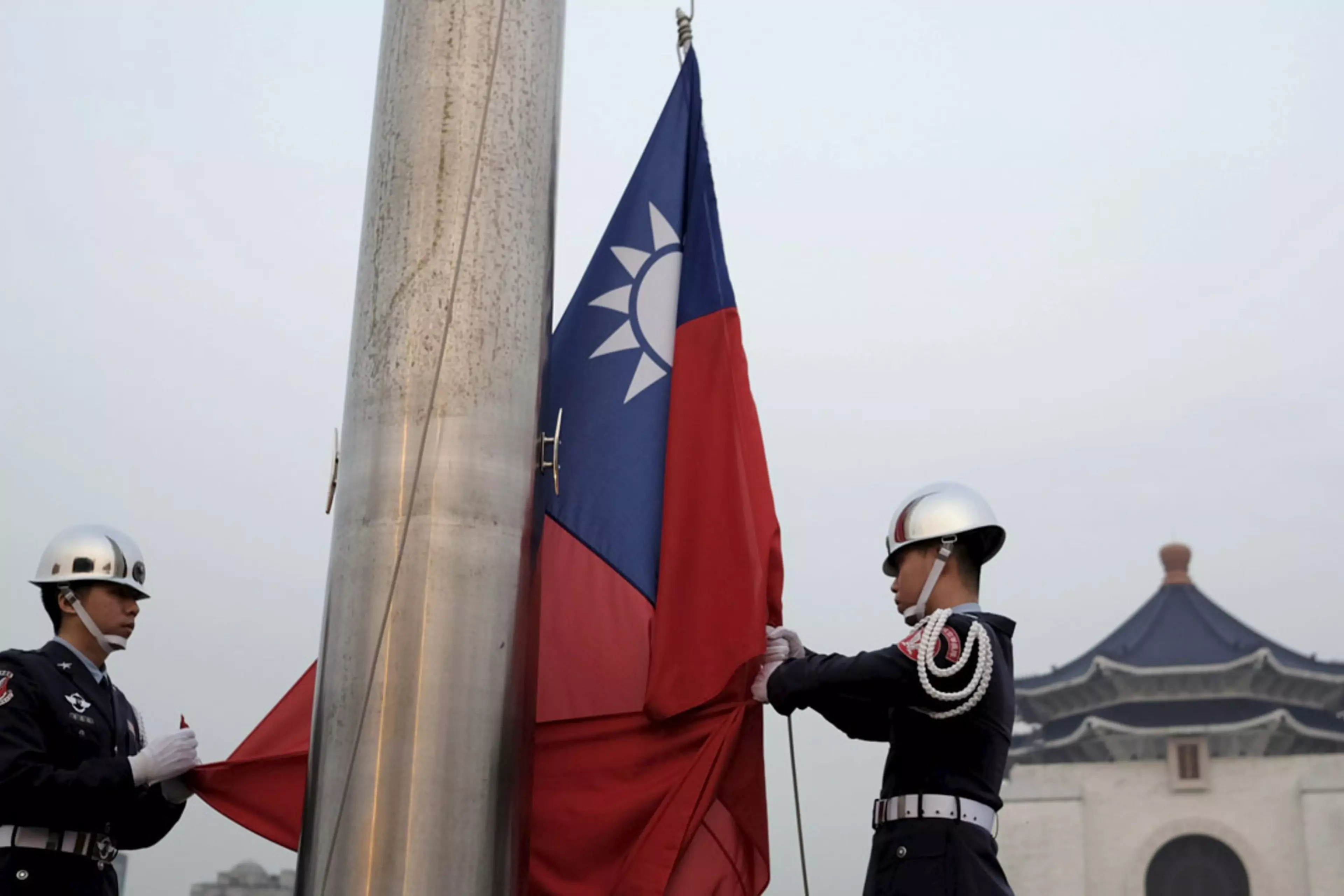 Military honor guards lower the Taiwanese flag in Taipei.