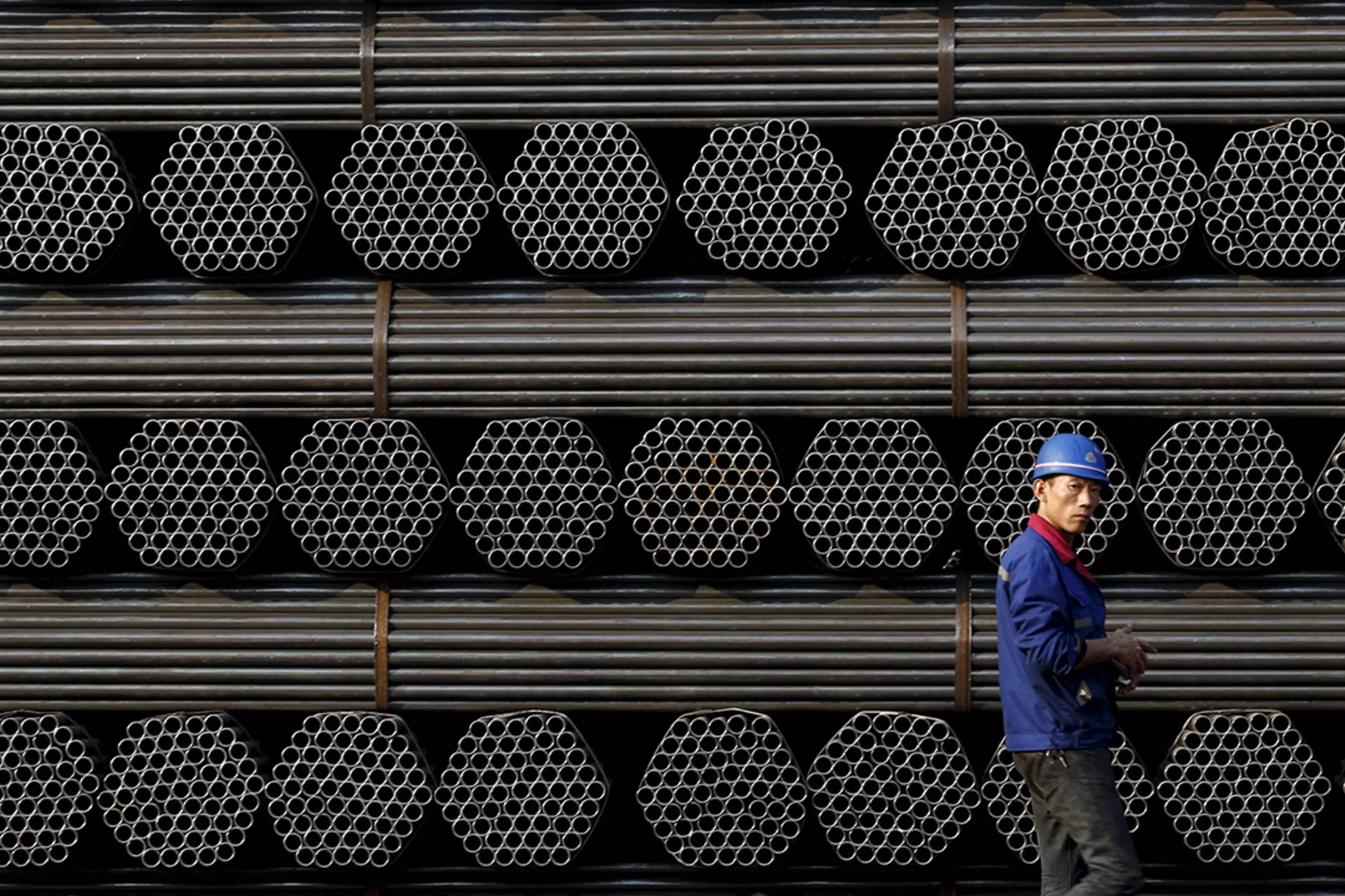 A worker stands in front of steel piping at a plant in China's Hebei Province.