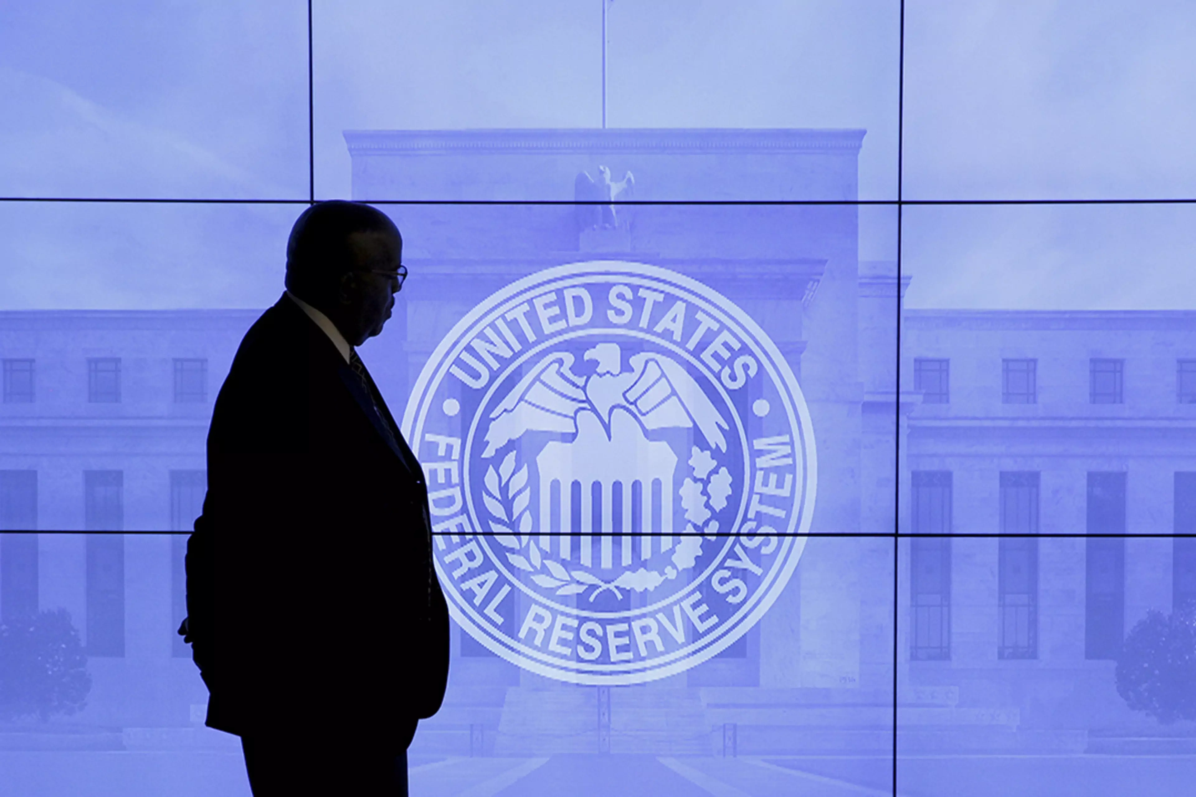 A security guard walks by an image of the Federal Reserve.