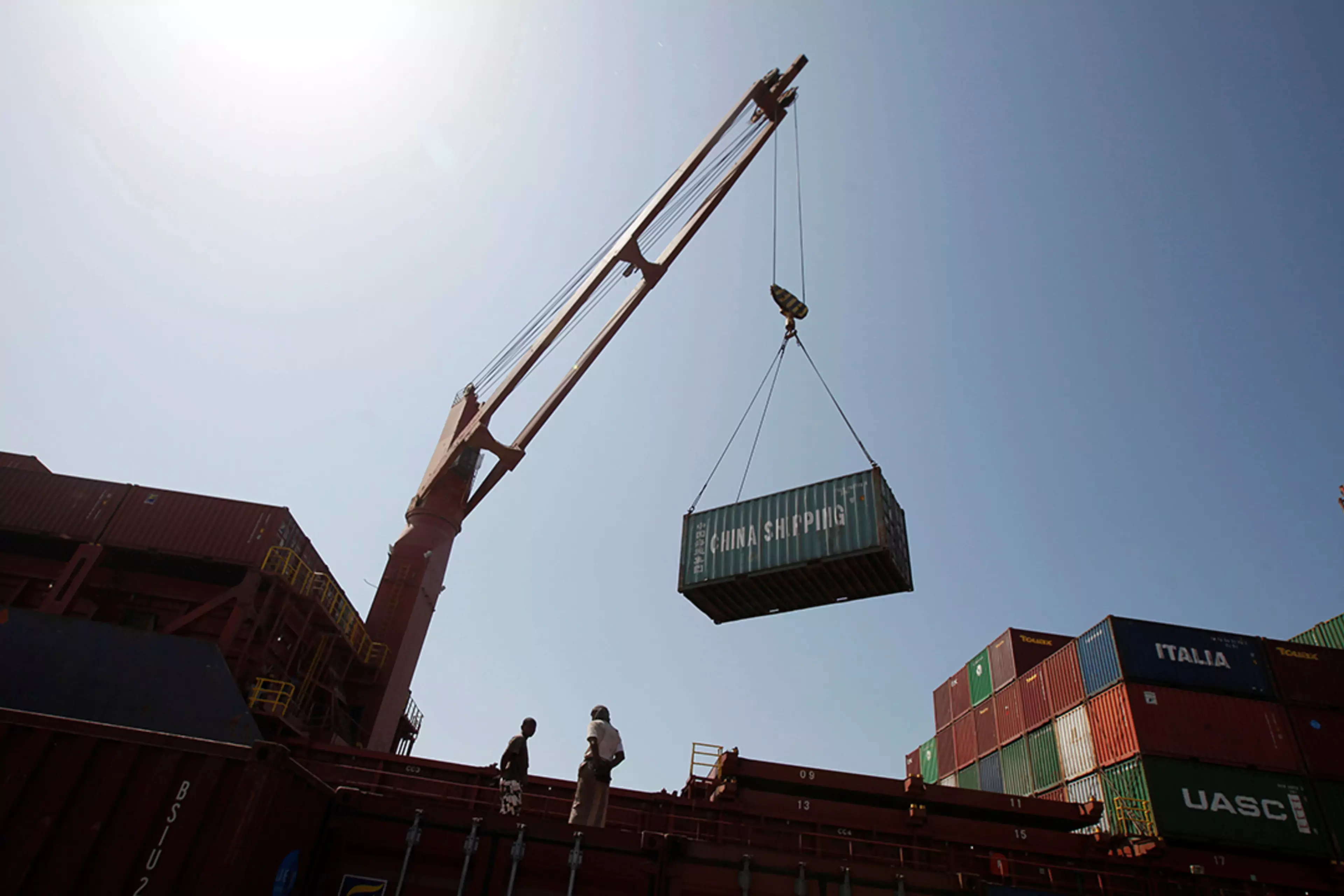 Workers use a crane to unload shipping containers at a port in Yemen.