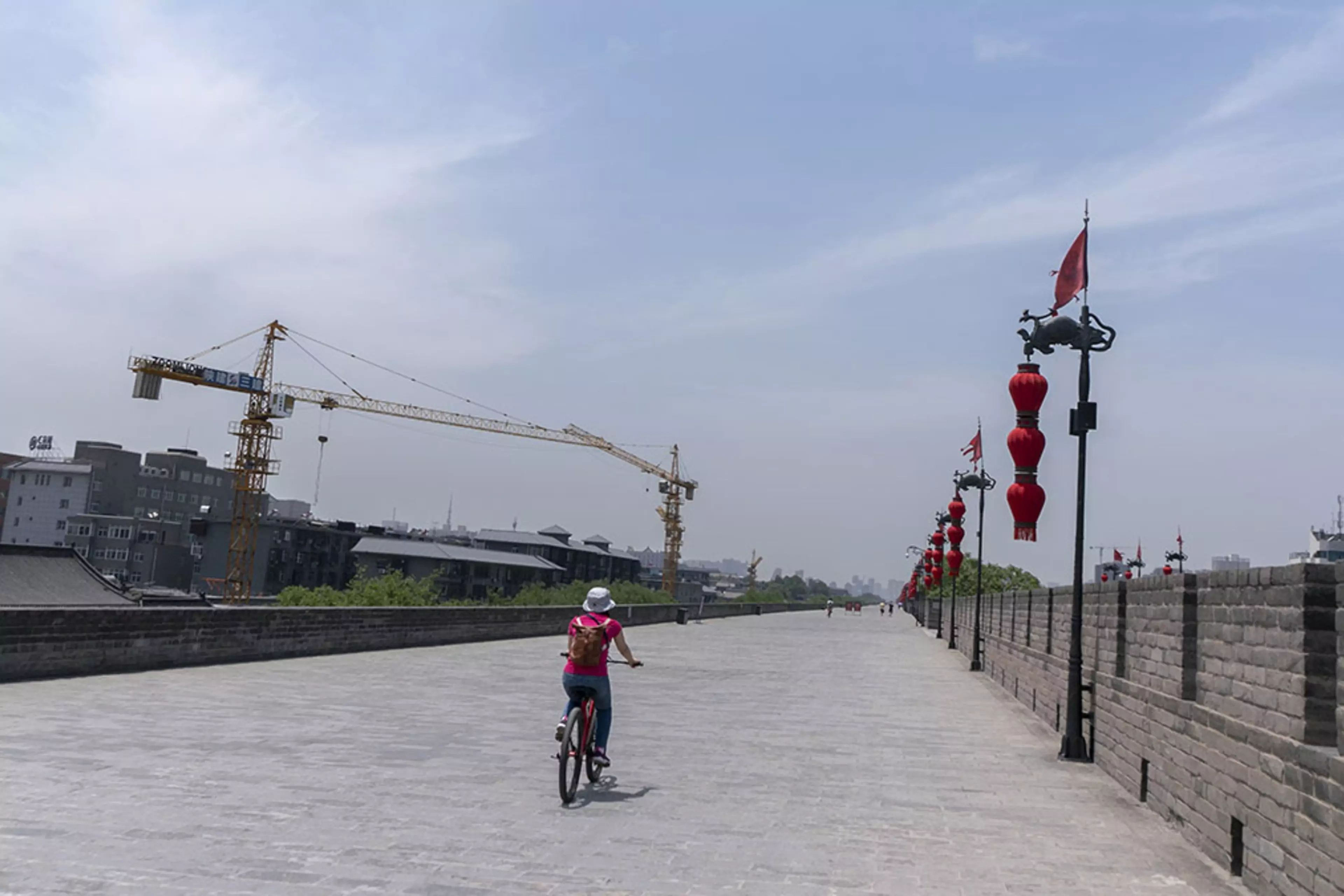 A cyclist passes by construction cranes in Xi'an, China.