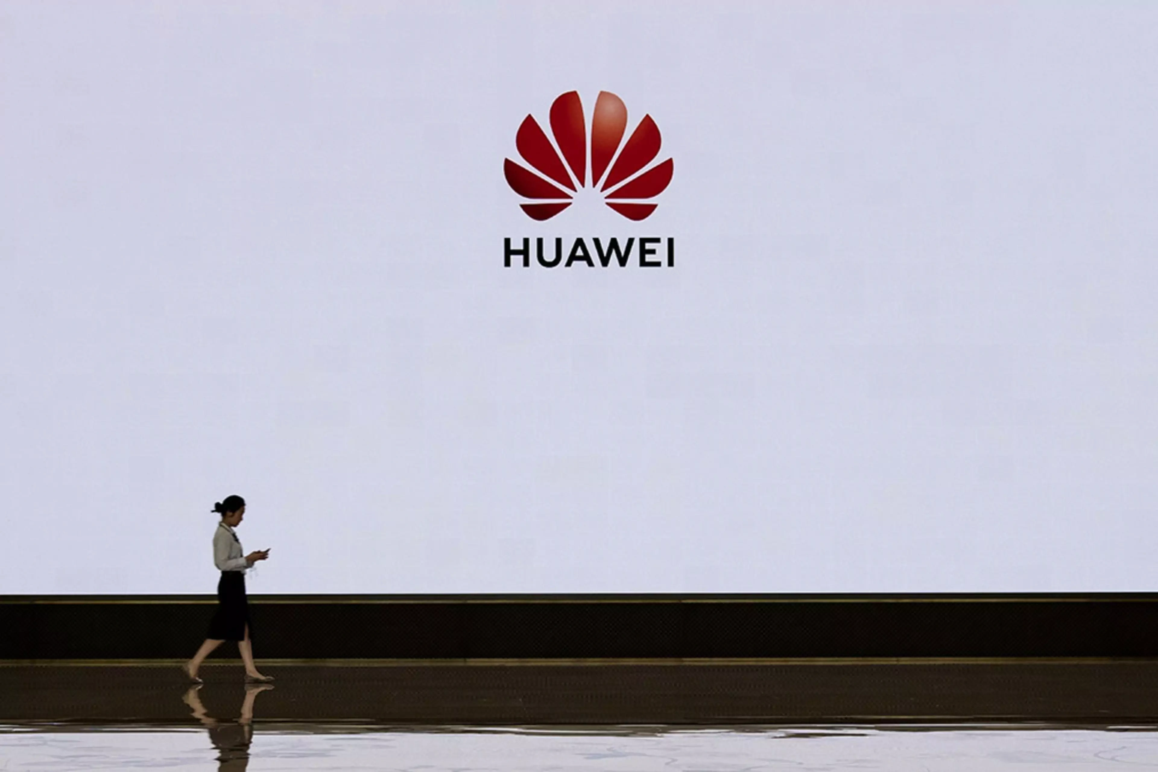 A Huawei employee walks by a screen displaying the company’s logo at its Shenzhen headquarters.