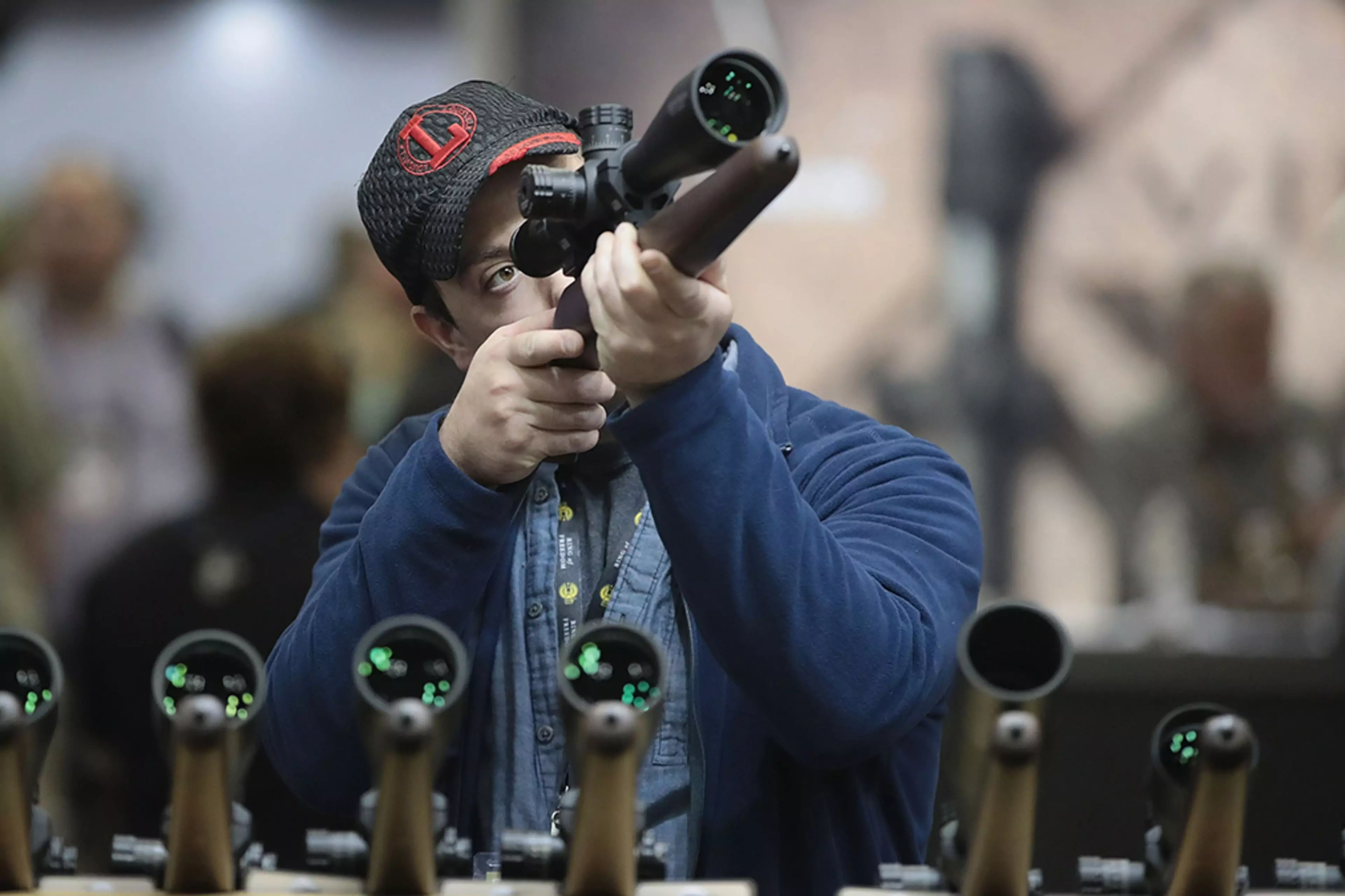 A gun enthusiast looks at a rifle scope during a 2019 National Rifle Association annual convention.