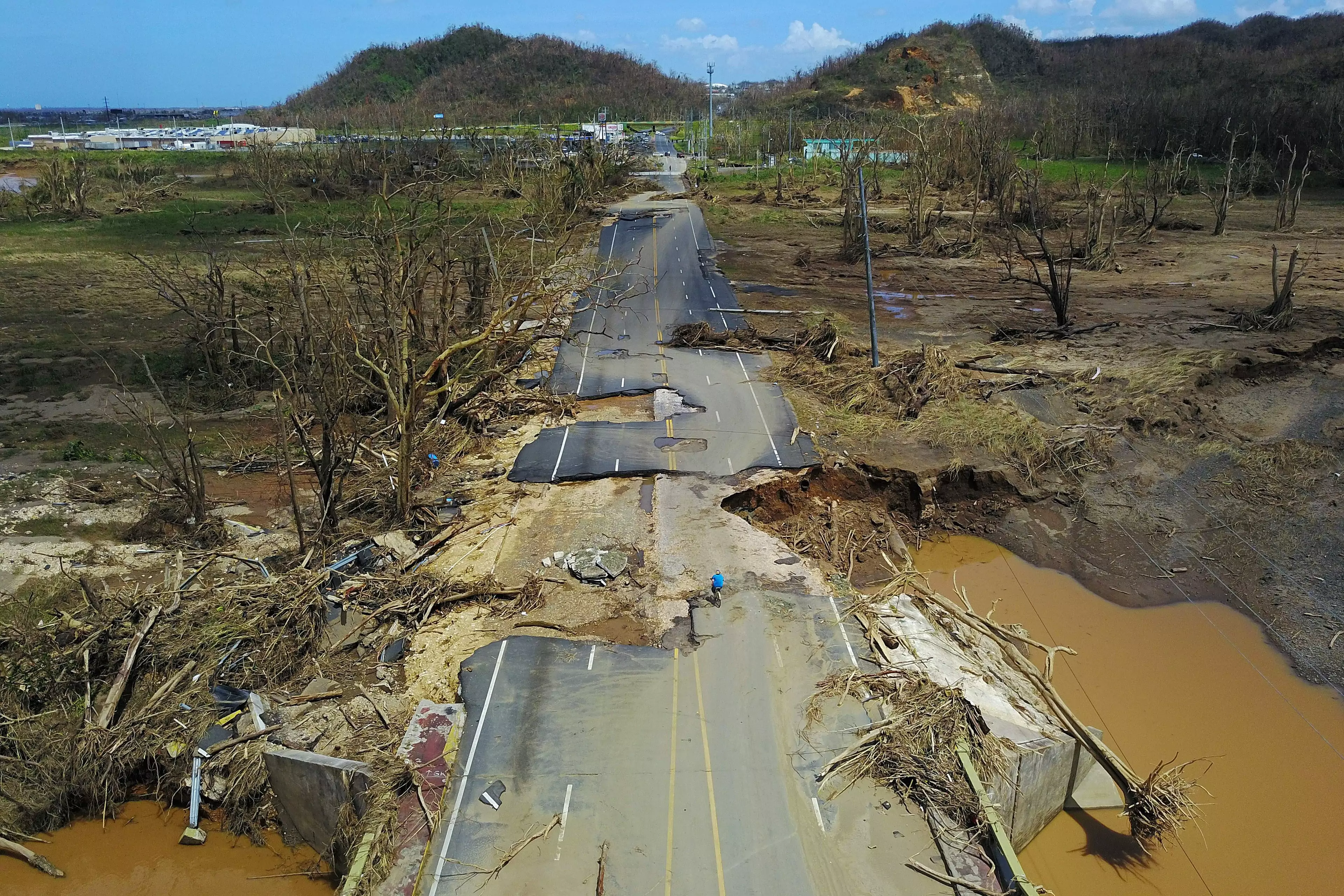 A man rides his bicycle on a damaged road in Puerto Rico after Hurricane Maria.