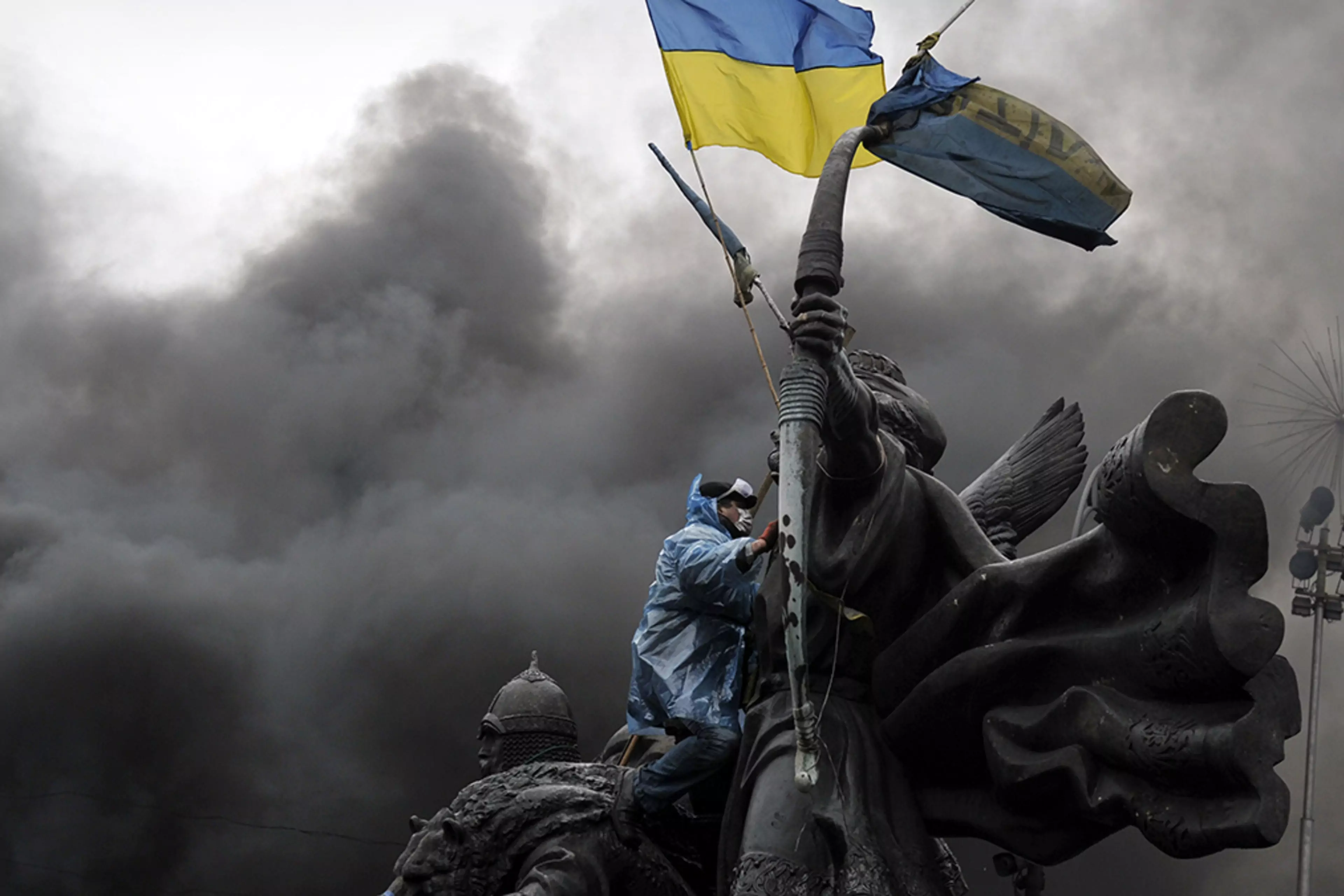 A protester sits on a monument in Kyiv during clashes with riot police in February 2014.