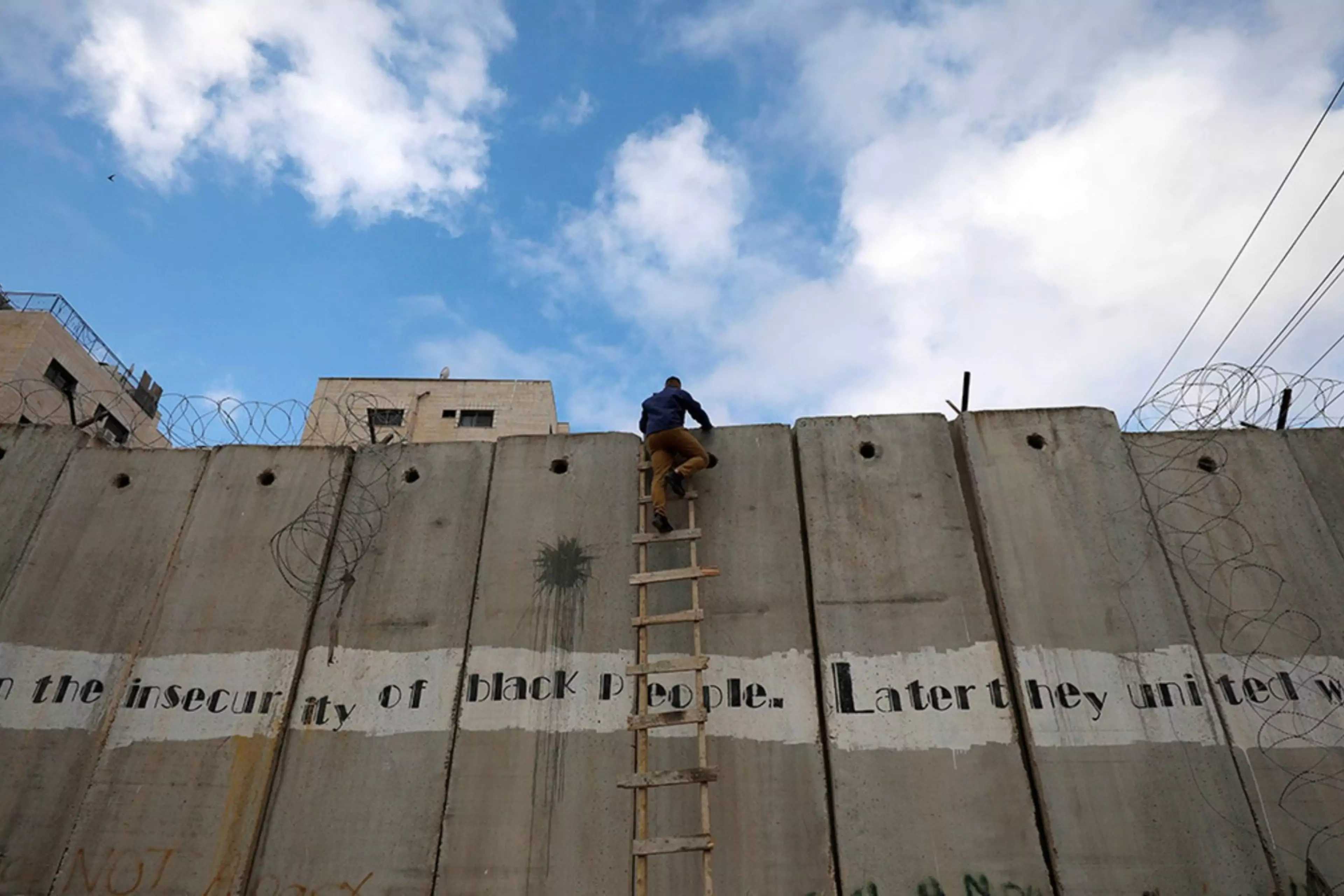 A Palestinian climbs the Israeli barrier in the Israeli-occupied West Bank.