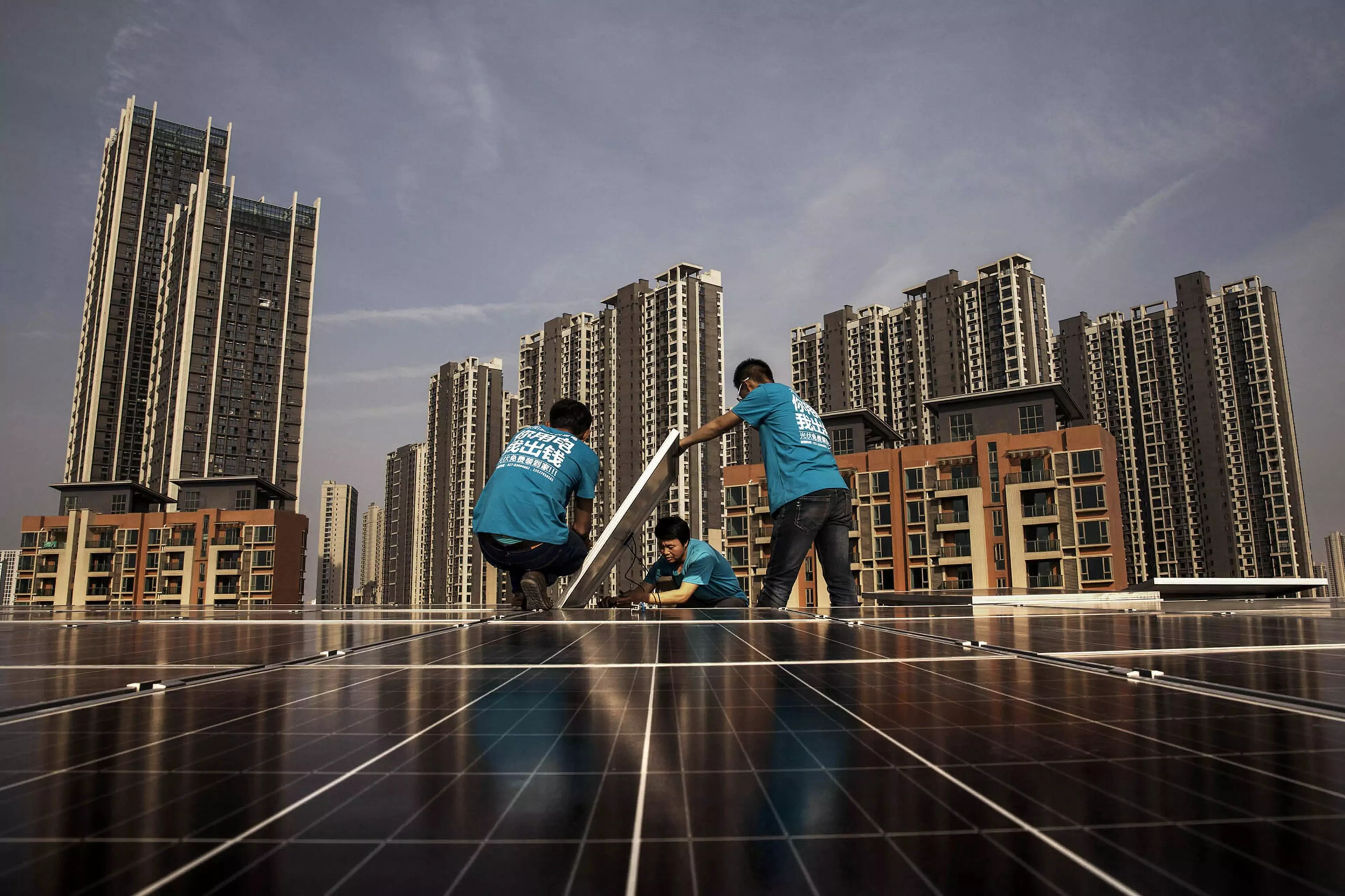 Workers install solar panels on a building’s roof in China.