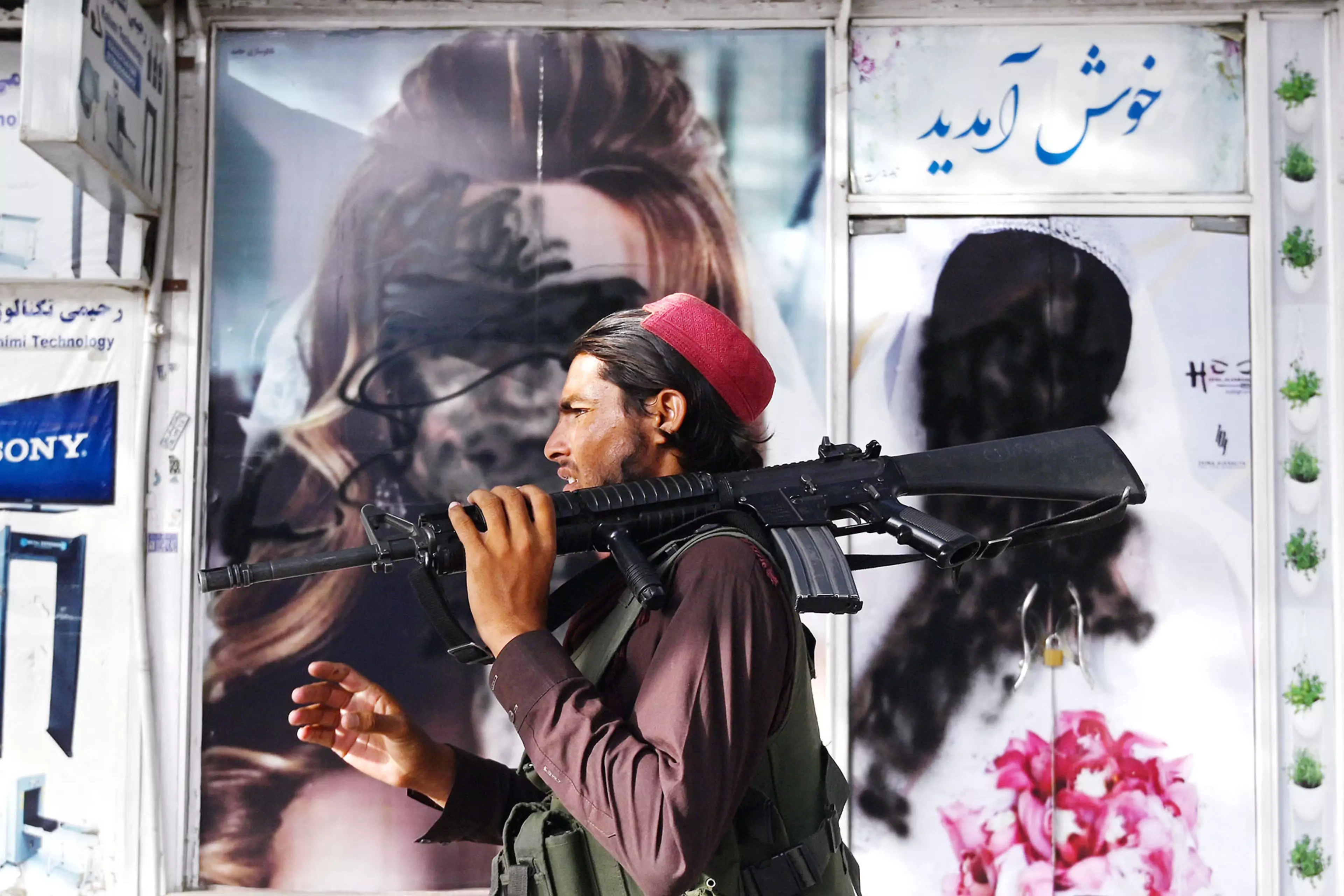 A Taliban fighter walks past a beauty salon after the Taliban seized Kabul in August 2021.