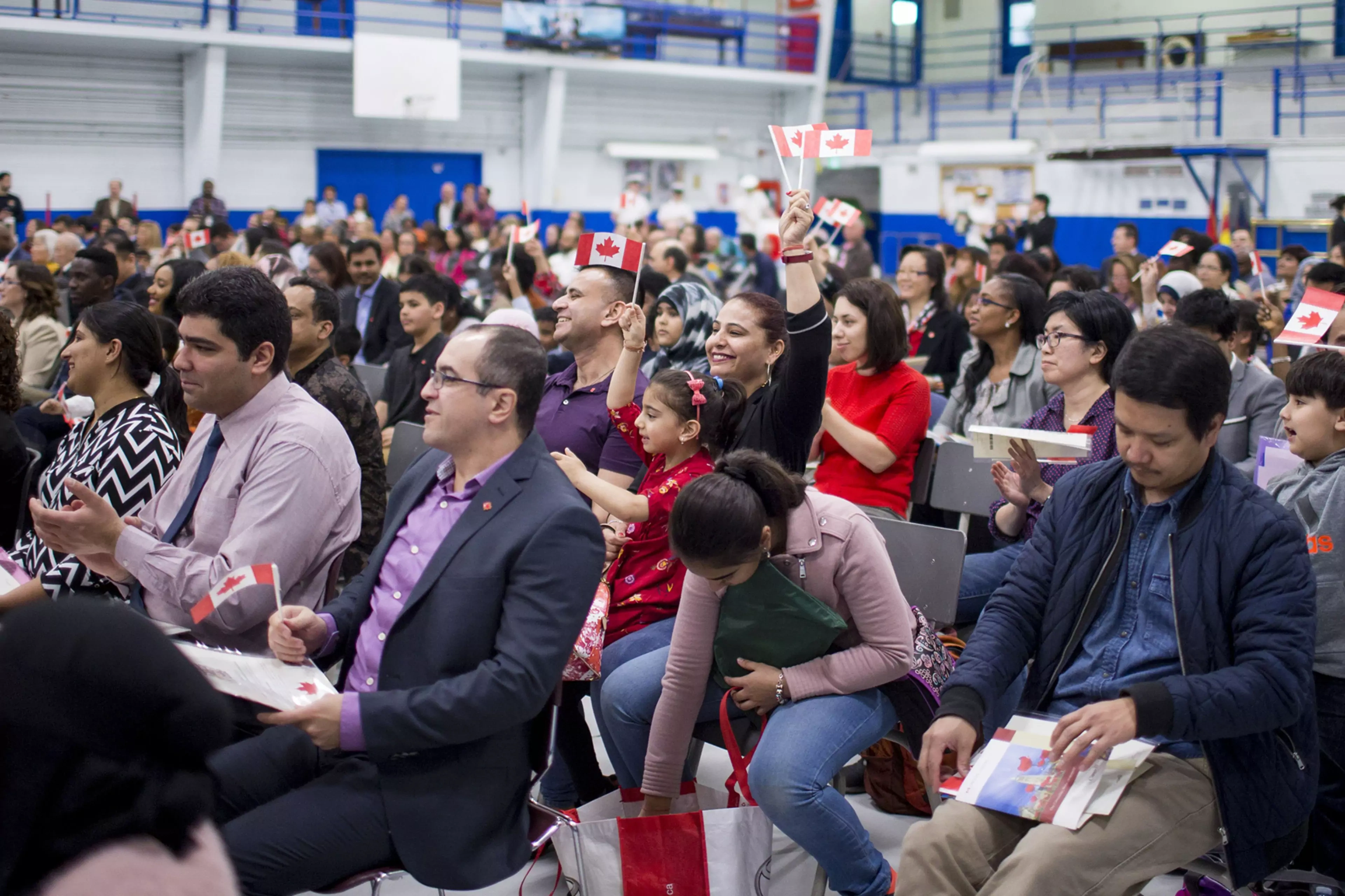 New Canadians wave the national flag during a citizenship ceremony in Toronto.