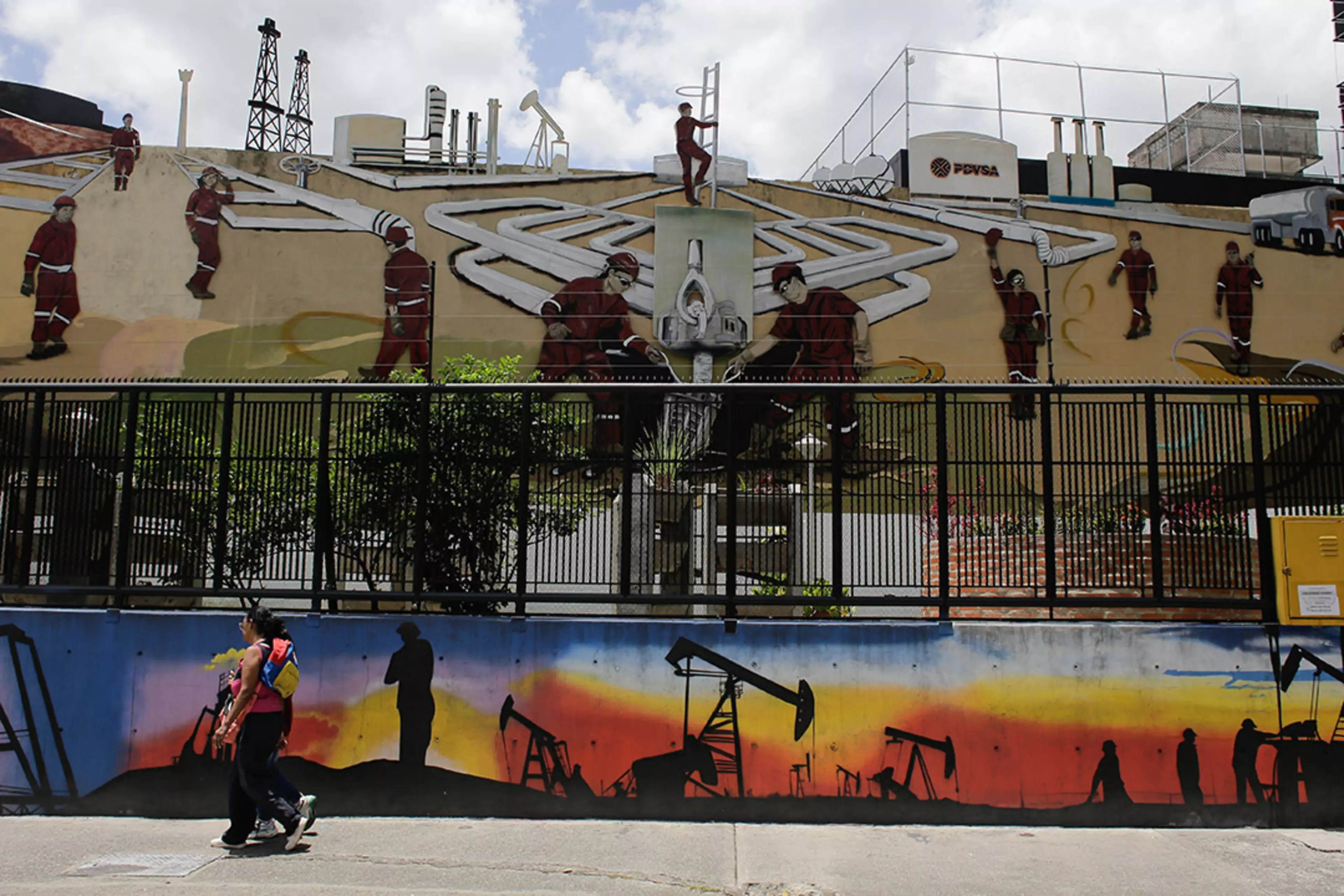 People walk past an oil-themed mural in Caracas, Venezuela.