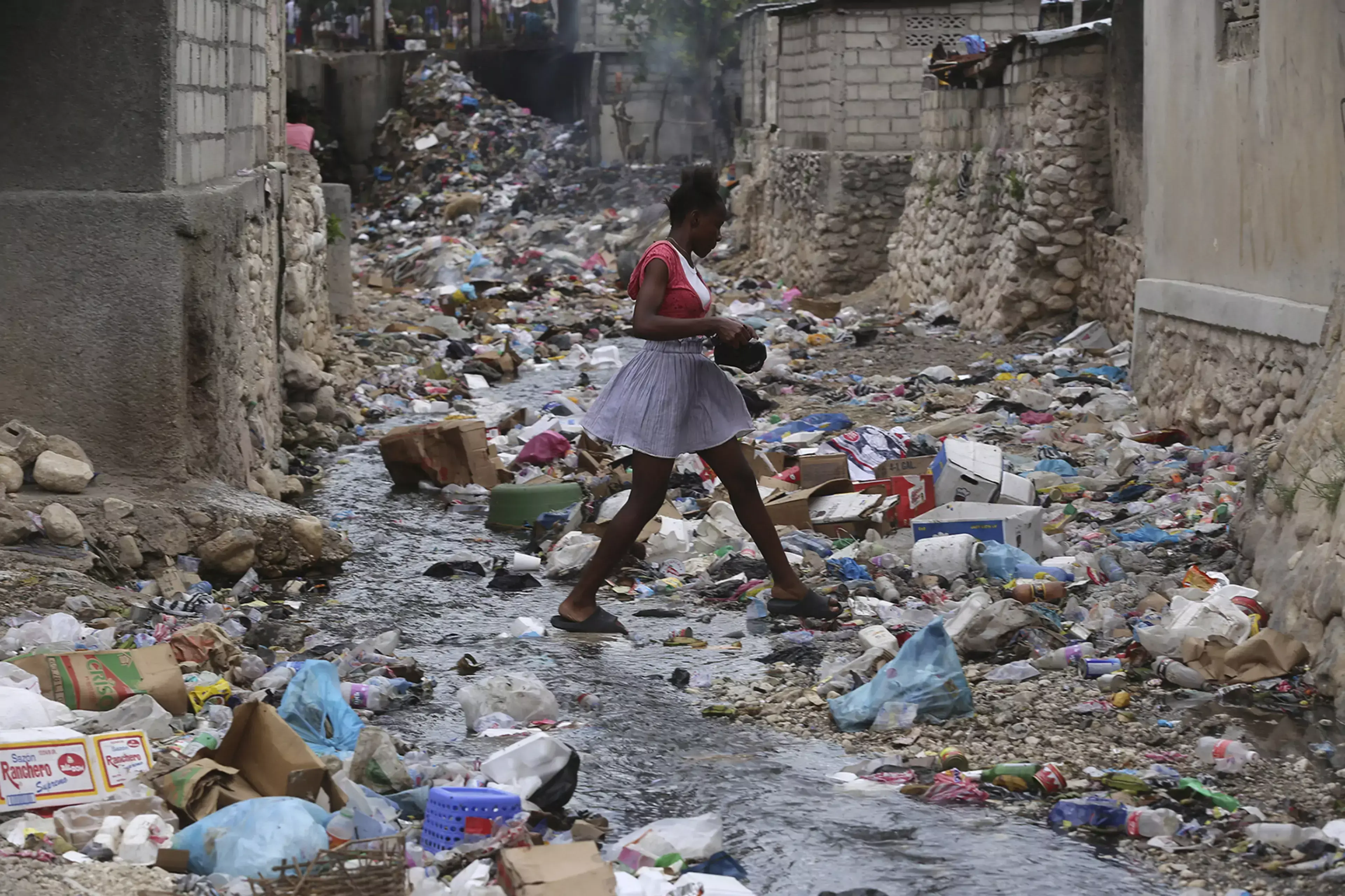 A Haitian girl walks through a garbage-filled ravine in Port-au-Prince.
