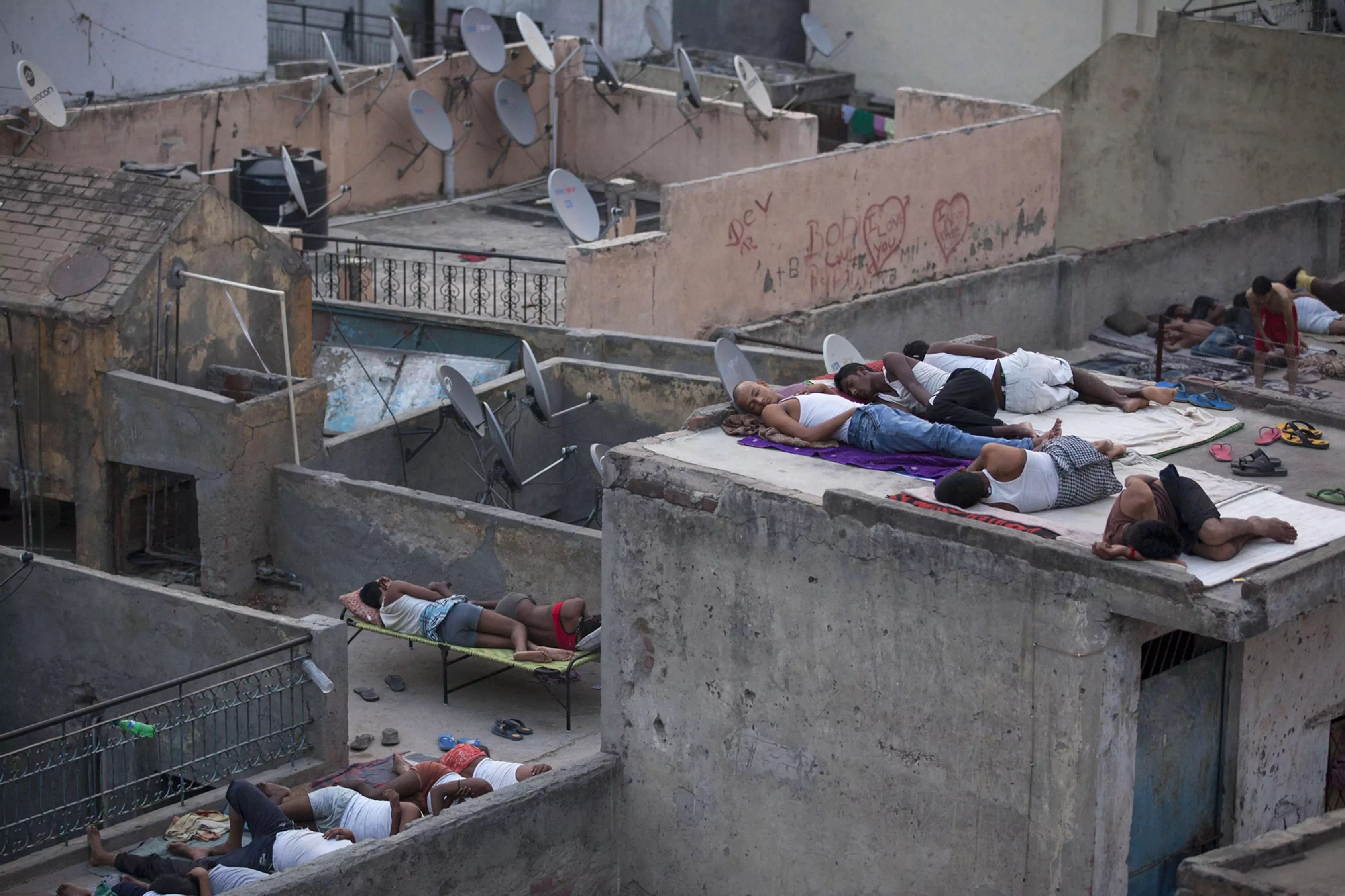 Indian men sleep on the roofs of houses to beat the heat in New Delhi,