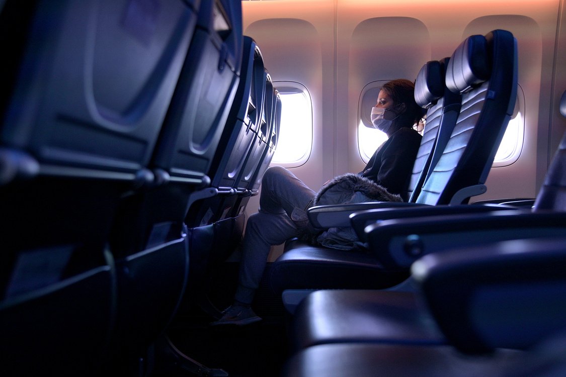 A masked passenger is seen seated on a flight from San Francisco, California to Newark