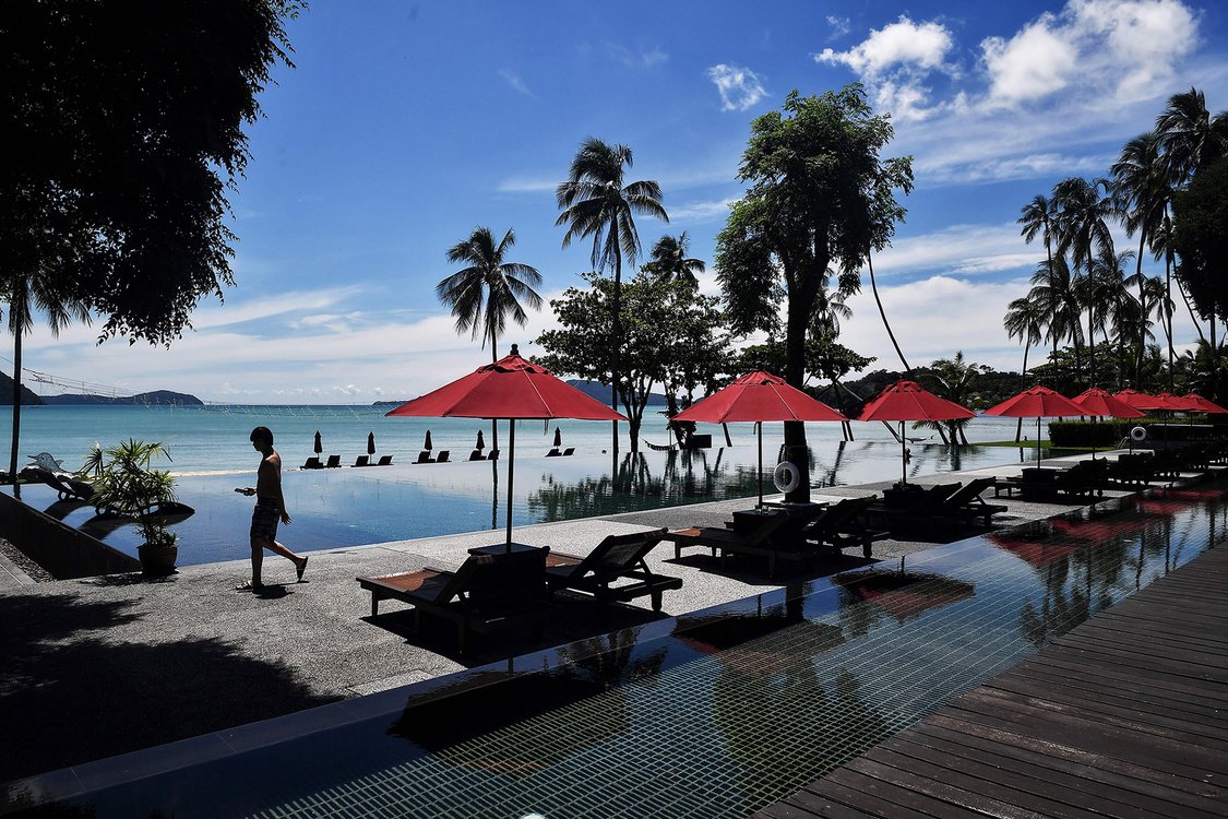 customer walking past a swimming pool at the Vijitt Resort in Phuket