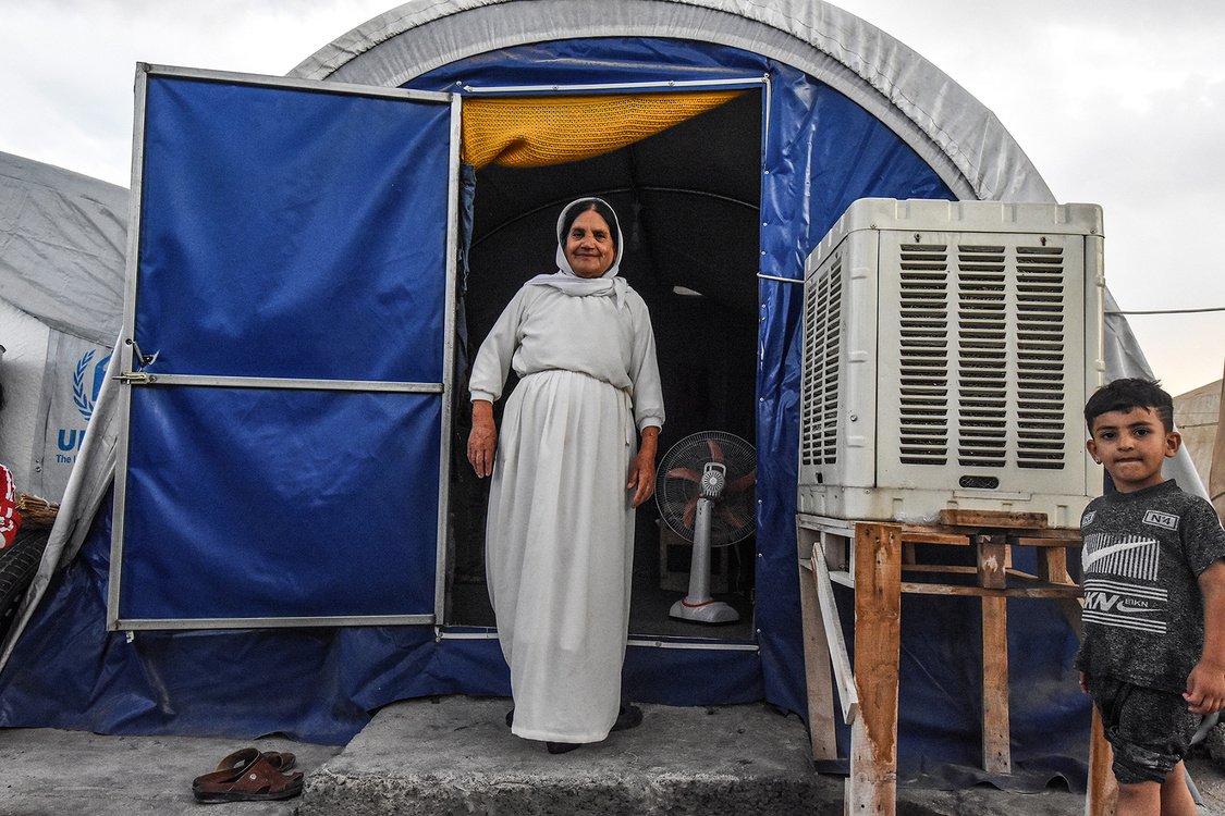 A woman stands through the doorway of a tent shelter equipped with air-conditioning at a camp for internally displaced persons in Kurdistan