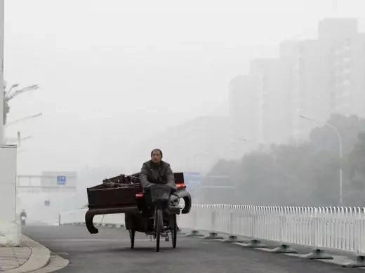 A man rides a tricycle carrying a couch on a road amid heavy smog in central Beijing on October 31, 2011.