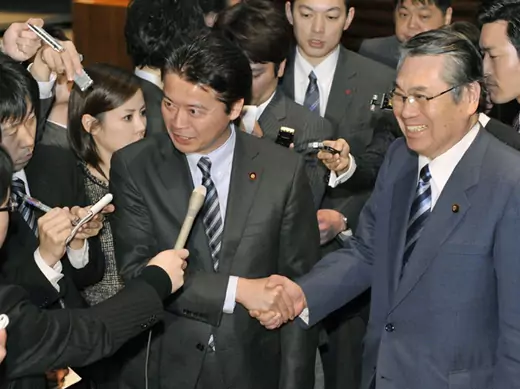 Japan's Foreign Minister Koichiro Gemba shakes hands with Defence Minister Naoki Tanaka as they are surrounded by media in Tokyo