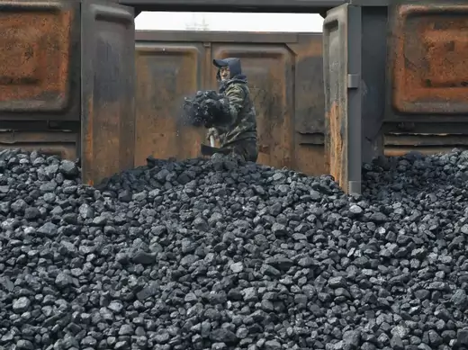 A worker unloads coal at a storage site along a railway station in Shenyang, Liaoning province on April 13, 2010.