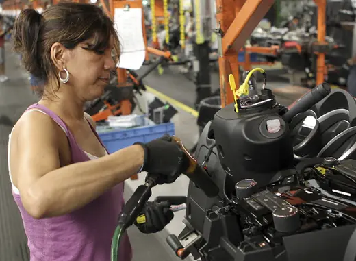 A worker installs parts onto the dashboard for a new car as it moves along the assembly line at a General Motors  assembly plant in Lordstown, Ohio (Aaron Josefczy/Courtesy Reuters).