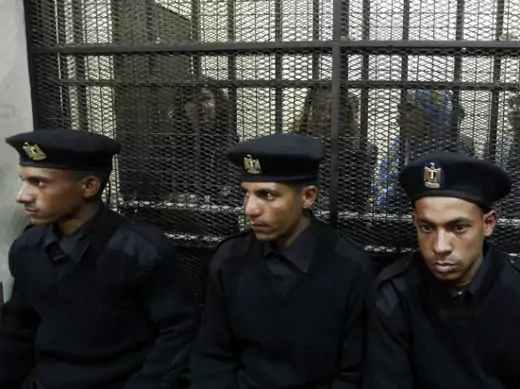 Some of the fourteen Egyptian activists who were accused of working for unlicensed non-governmental organizations and receiving illegal foreign funds, stand in a cage during the opening of their trial in Cairo on February 26, 2012 (Mohamed Abd El Ghany/Courtesy Reuters).