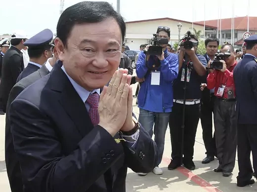 Former Thai prime minister Thaksin Shinawatra greets the media upon his arrival at the Siem Reap International Airport in Cambodia, April 14, 2012. Thailand's fugitive former premier Thaksin took some small but symbolic steps towards the fringes of his homeland on Wednesday after five years in exile.